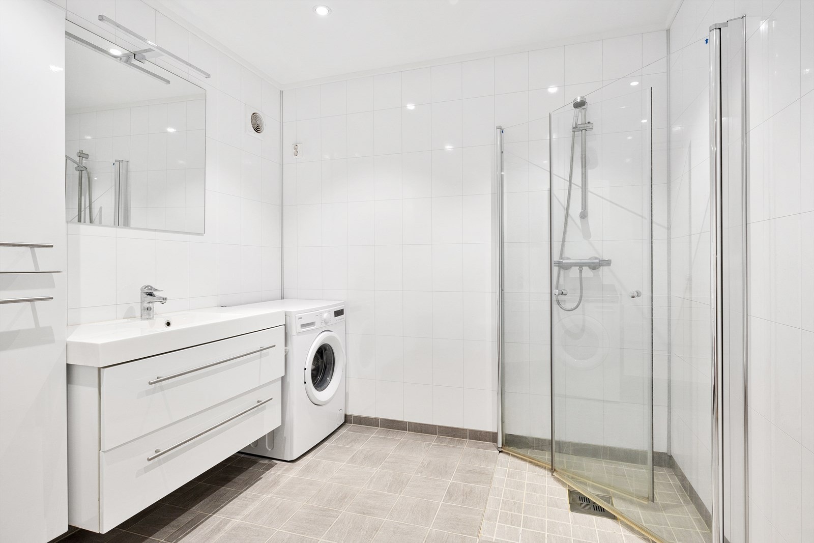 Flislagt bad med dusjhjørne og opplegg for vaskemaskin Galleribilde