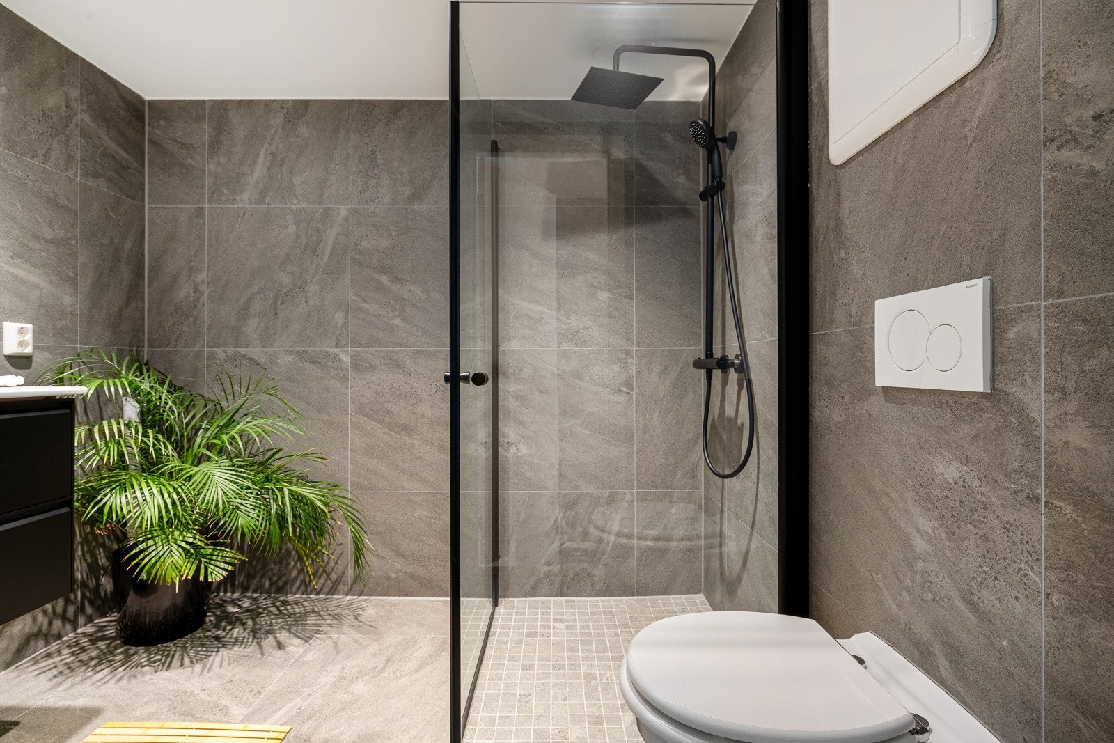 Badet er helfliset og er innredet med vegghengt servantinnredning, dusjhjørne og vegghengt toalett. Galleribilde