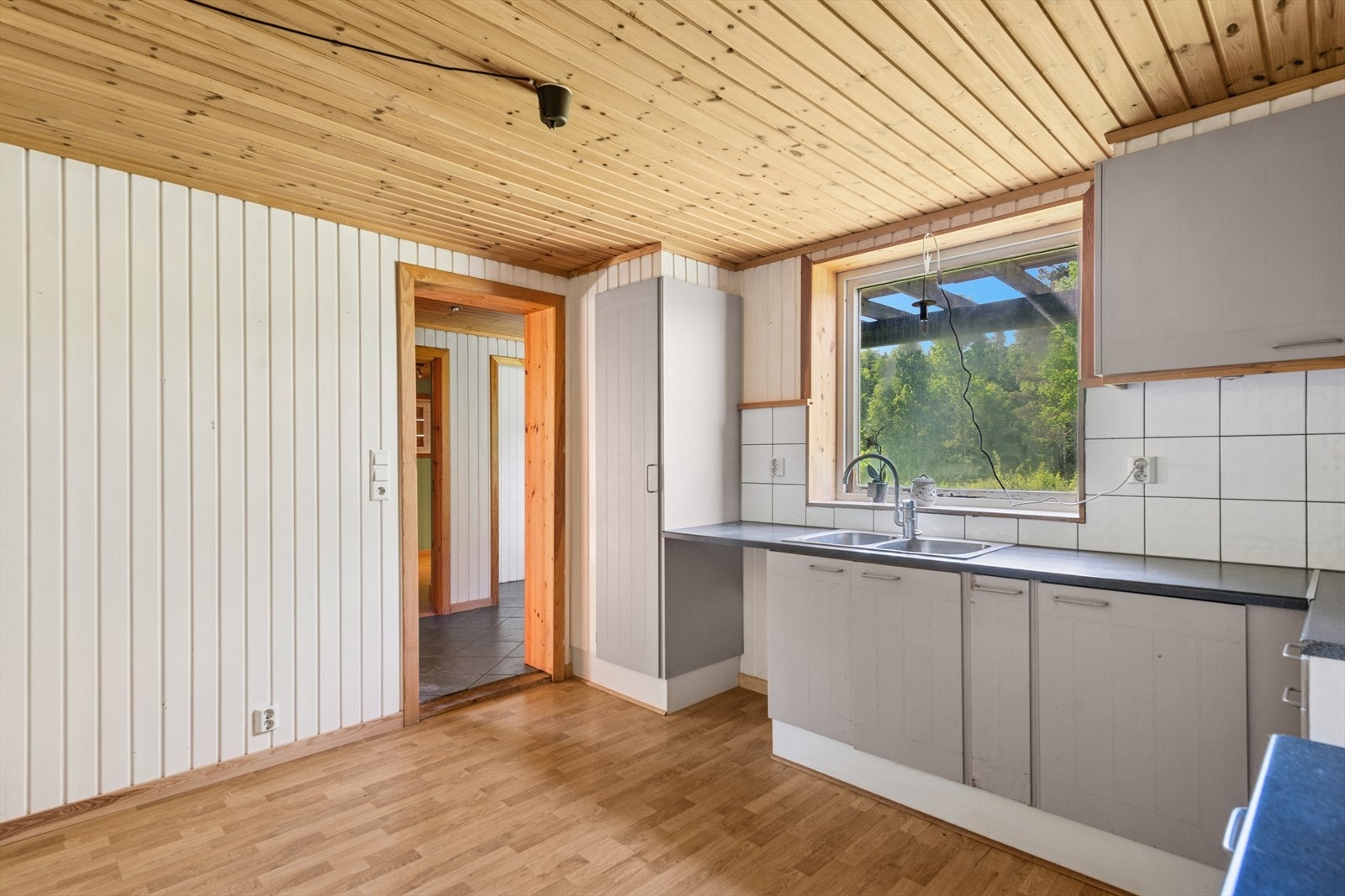 Kjøkkeninnredningen har malte fronter og en laminert benkeplate, utstyrt med dobbel vaskekum og kjøkkenkran. Galleribilde