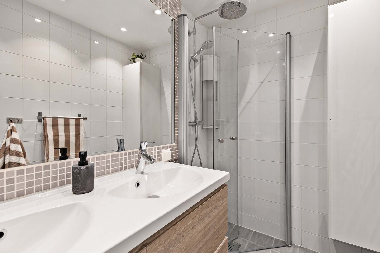Badet er innredet med servant nedfelt i innredning og dusjhjørne med svingbare glassdører. Galleribilde