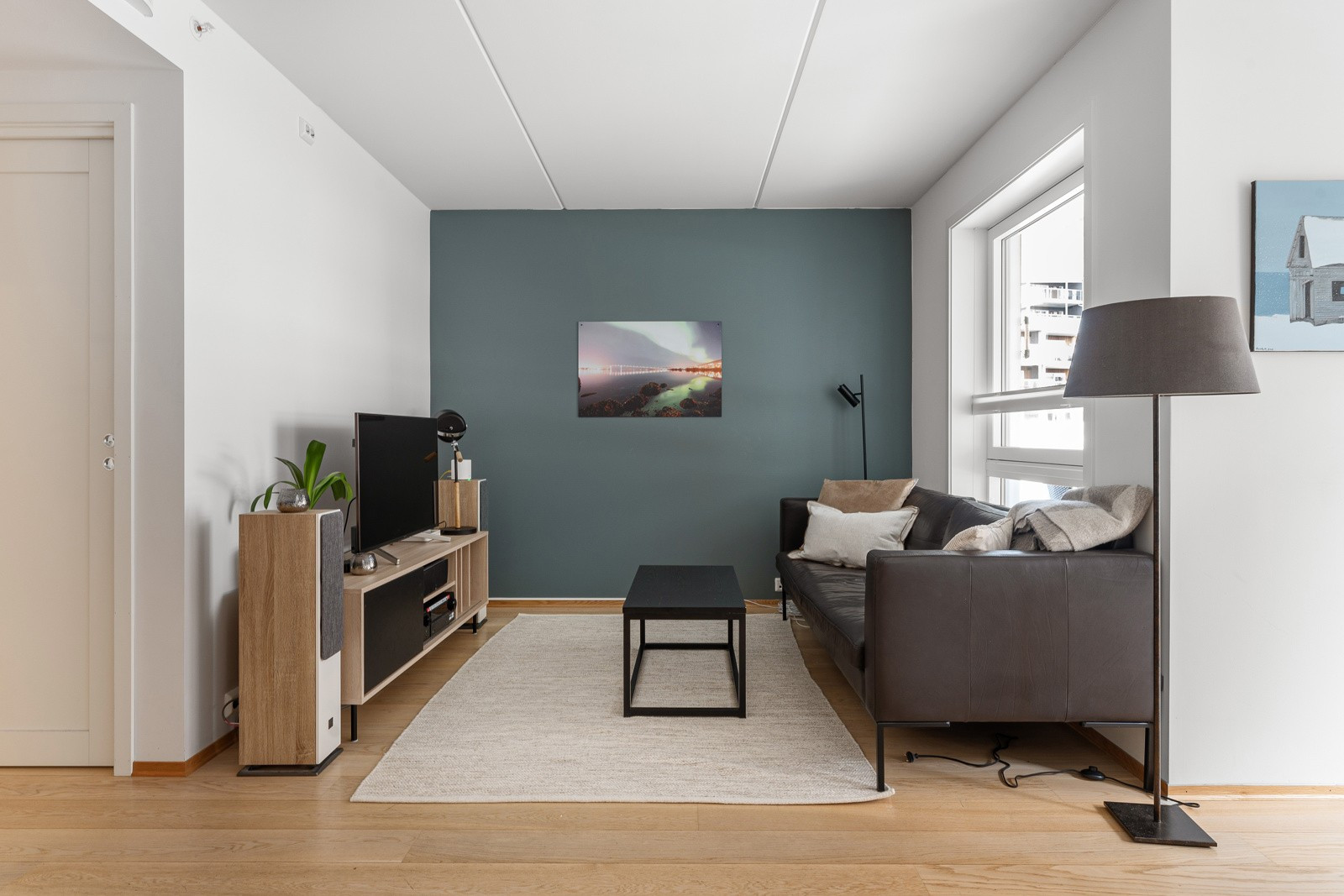 Stuen framstår åpen, lys og luftig, med store vindusflater og generøs takhøyde.