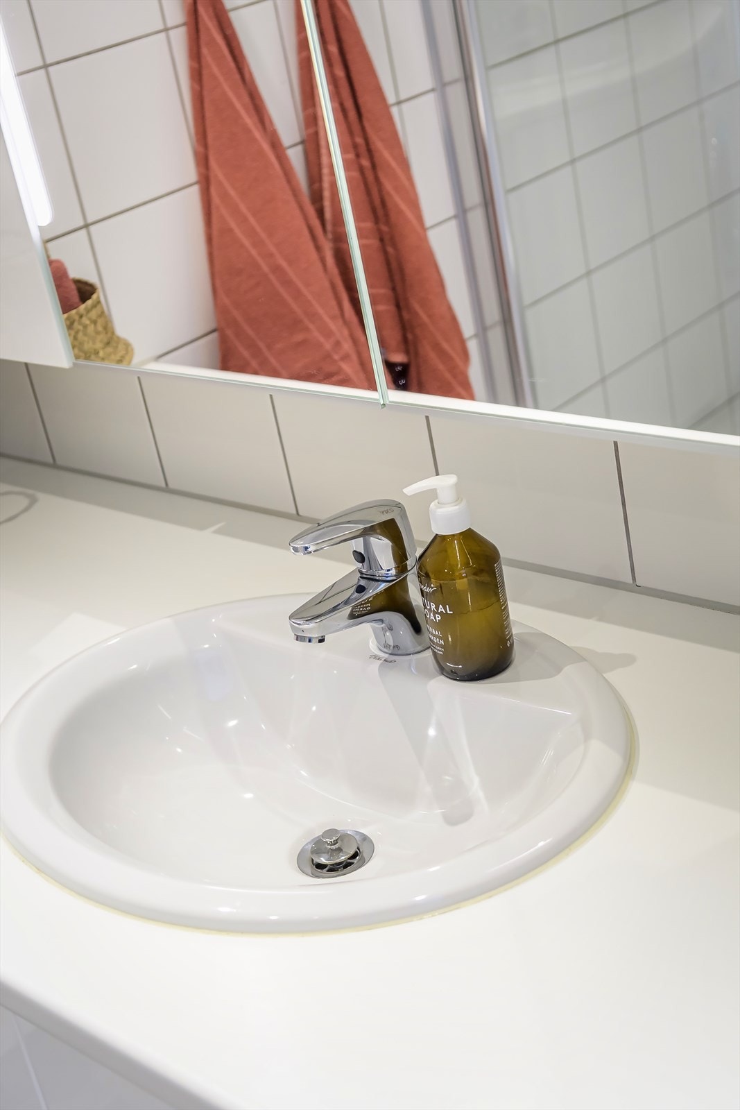 Rommet er innredet med veggmontert klosett, nedsenket vask med innredning og speil, dusjnisje med glassdører og opplegg til vaskemaskin og tørketrommel. Galleribilde