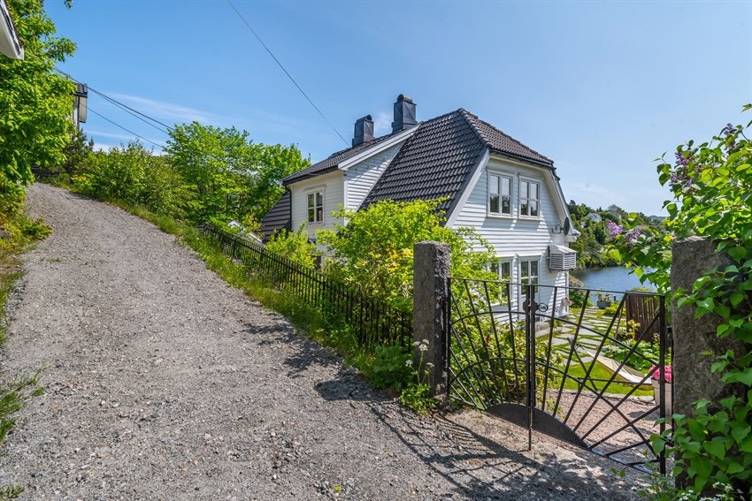 Gruset bakke fra garasje og ned til eiendommen. Galleribilde