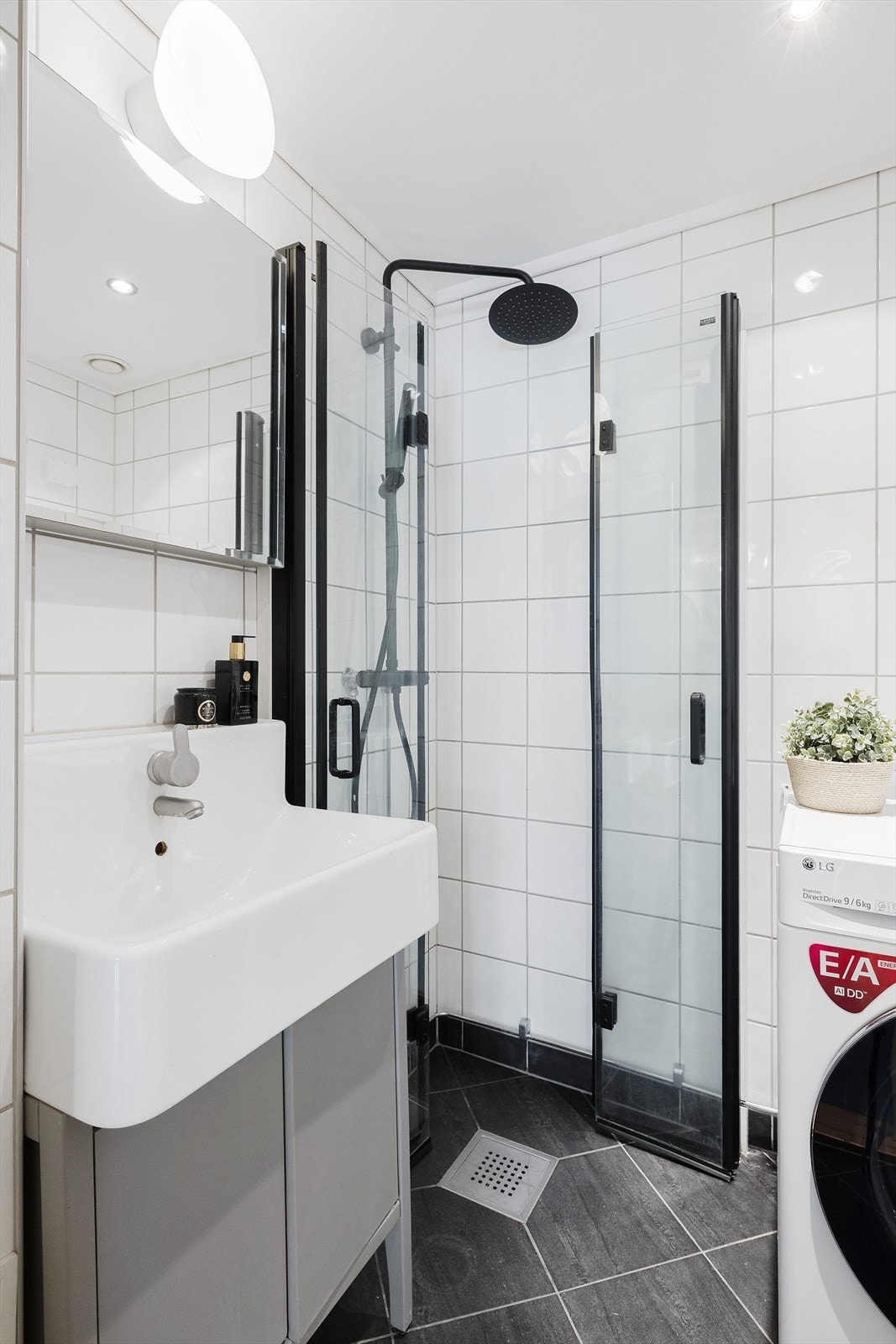 Badet har praktisk dusjhjørne med innfellbare dusjdører, servant med innredning, opplegg for vaskemaskin og varmekabler i gulv Galleribilde