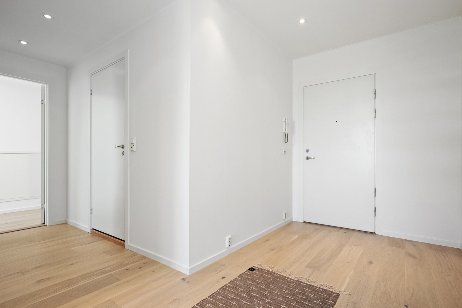 Vel inne blir vi ønsket velkommen i en luftig, flott hall med hvitmalte, glatte overflater, downlights i himlingen og gyllen, enstavs parkett på gulv med vannbåren gulvvarme Galleribilde