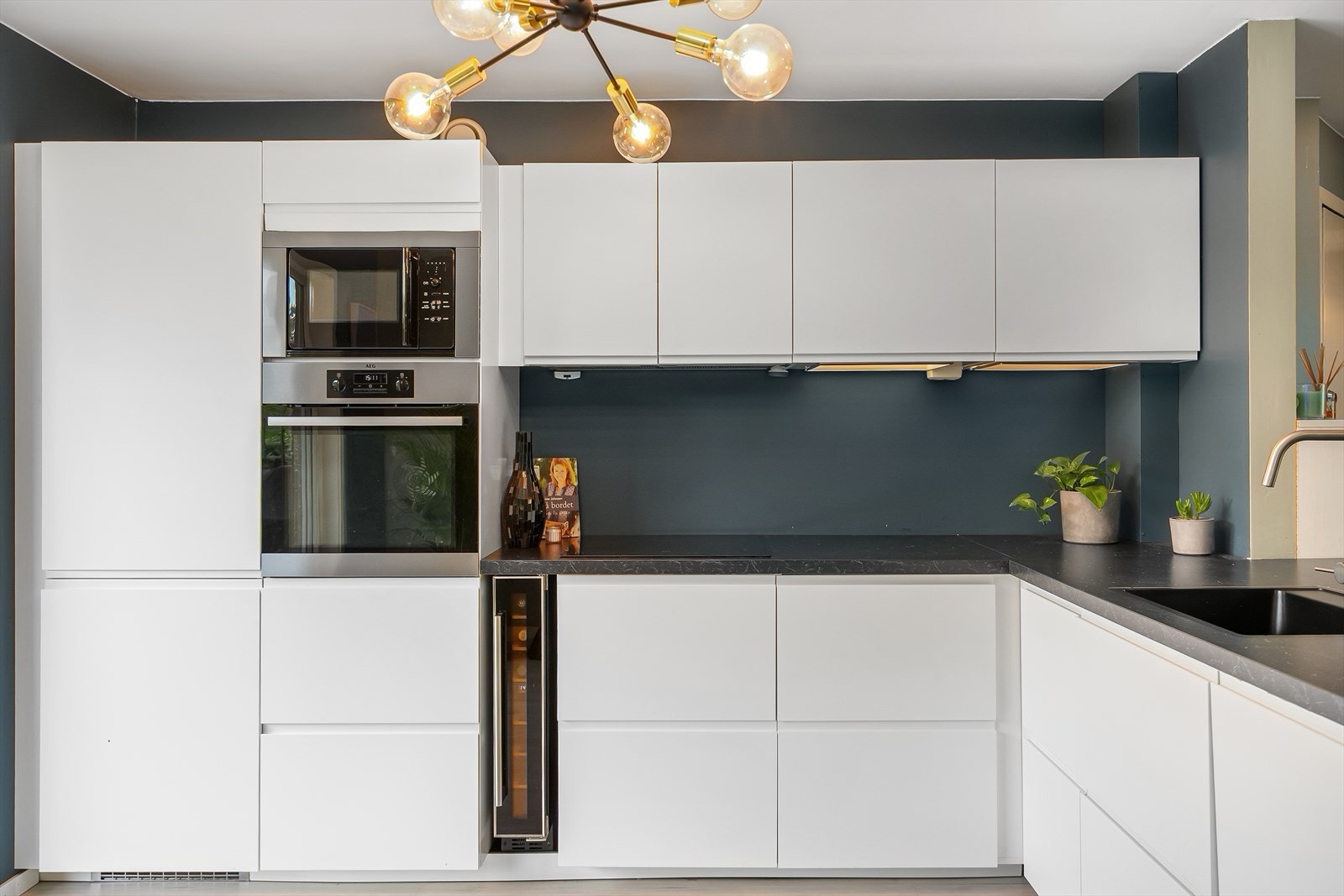 IKEA kjøkken fra 2019 med lyse fronter. Det er integrert kjøl/fryseskap, oppvaskmaskin, mikroovn, vinskap, stekeovn og platetopp Galleribilde