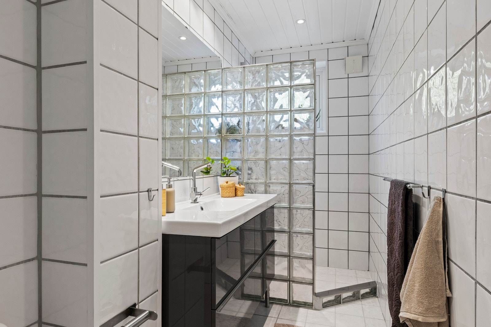 Bad utstyrt med servant med slette fronter, gulvstående toalett og dusjvegger i hjørneløsning Galleribilde