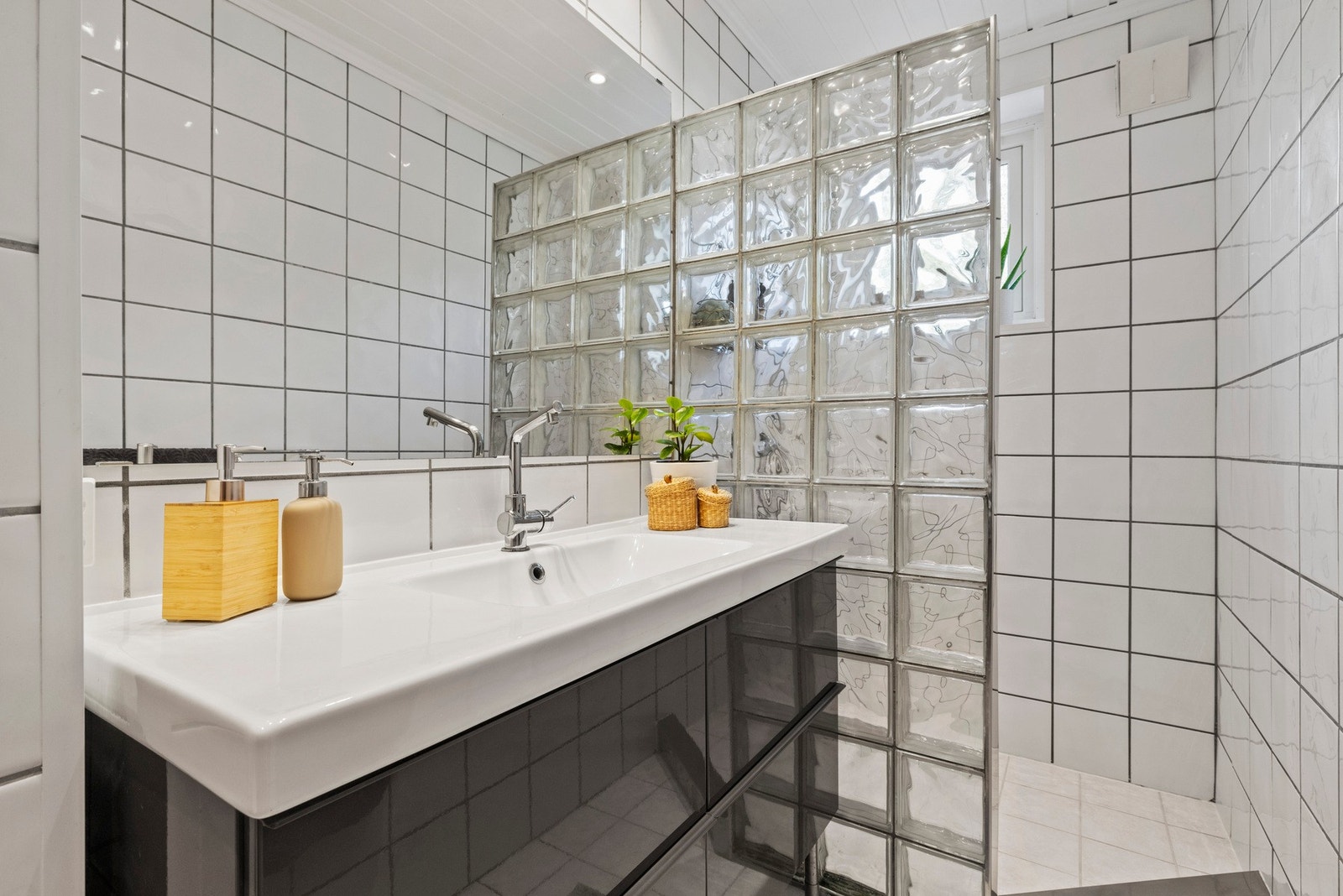 Rommet er utstyrt med en servant med slette fronter, gulvstående toalett og dusjvegger i hjørneløsning Galleribilde