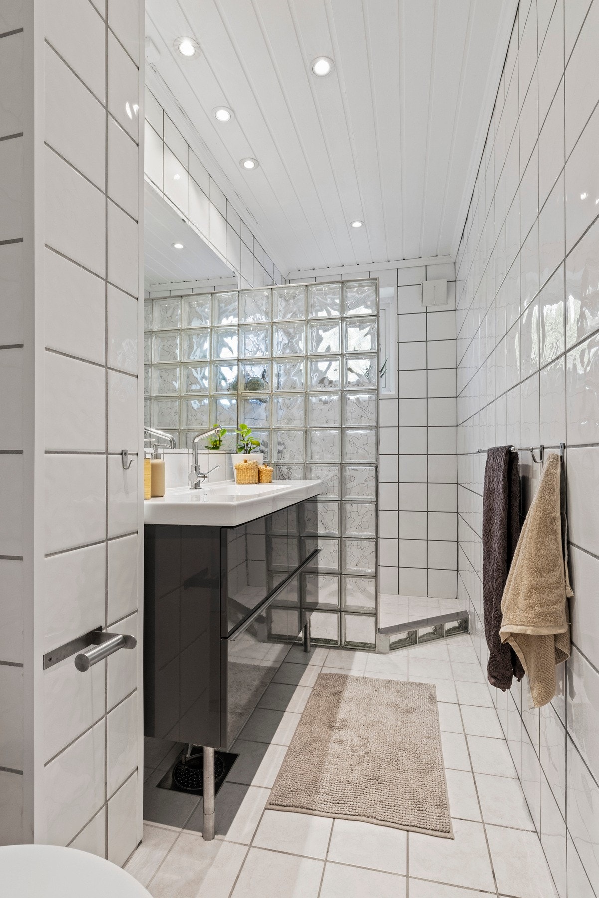 Badet har flislagte vegger og gulv, med panel i taket og integrerte downlights som gir jevn belysning Galleribilde