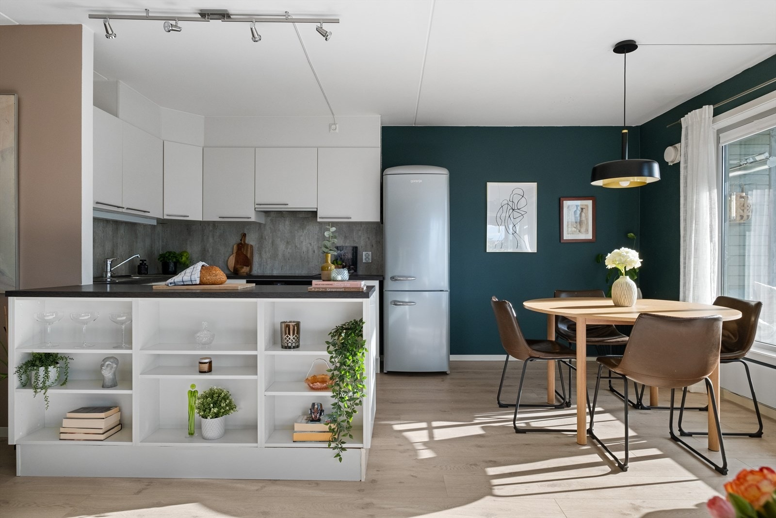 Kjøkkeninnredning med glatte fronter, laminat benkeplate med nedfelt vask-og skyllekum, samt våtromsplate og belysning over benkeplaten. Galleribilde