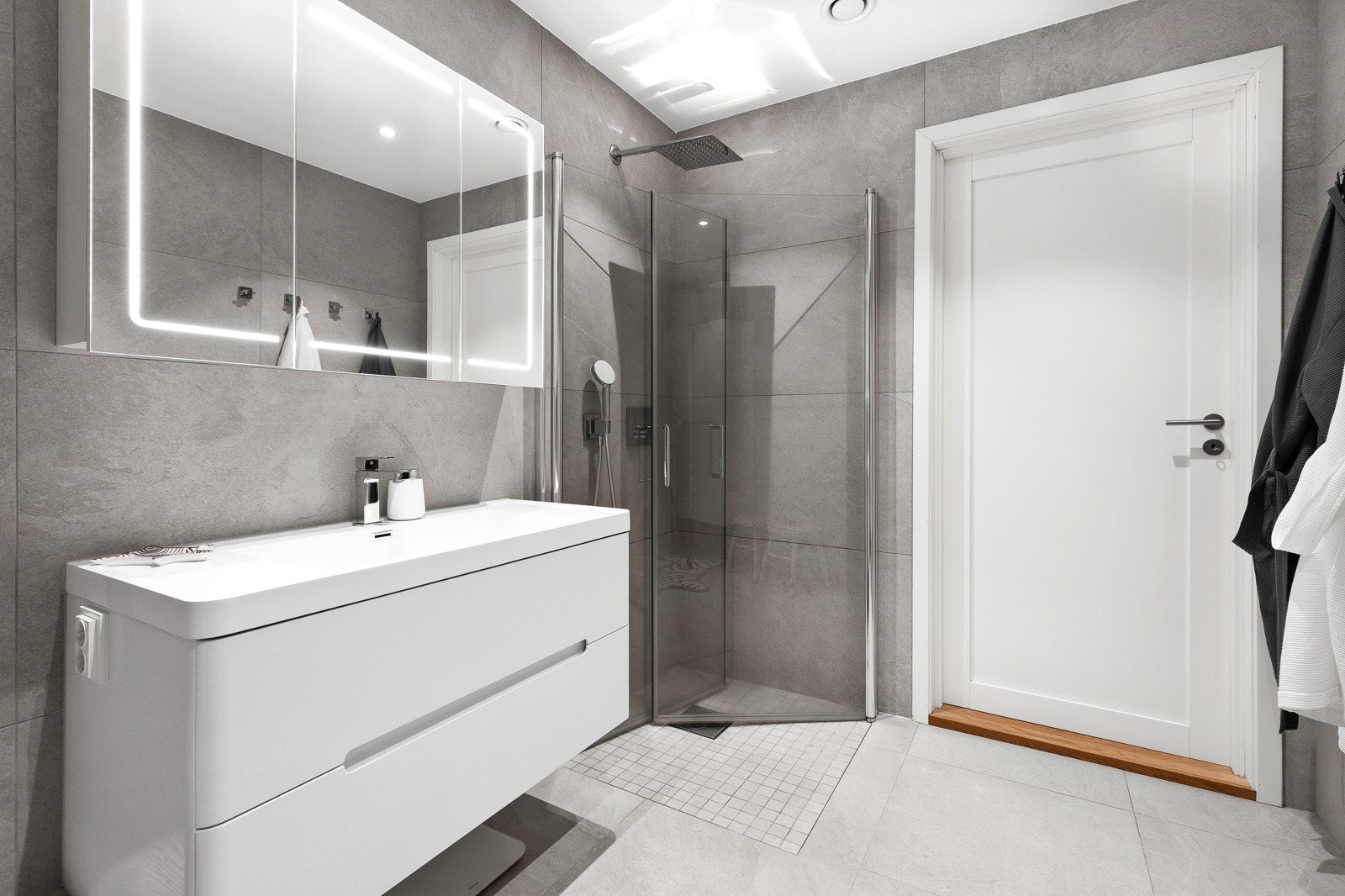 Badet har vegghengt servant og regnfalldusj. Galleribilde