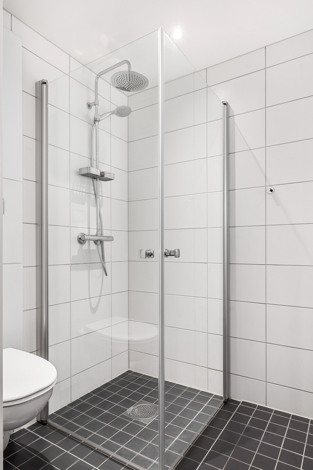 Rommet har dusjhjørne med glassdører, toalett, servantskap og opplegg for vaskemaskin. Galleribilde