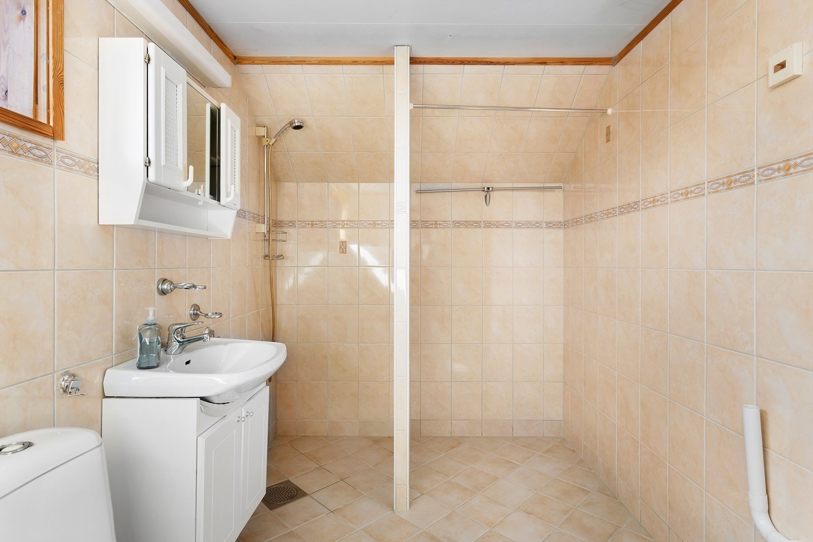 Badet er innredet med servantskap med profilerte fronter, overlimt servant med ettgreps blandebatteri, veggskap med speil og lys på vegg Galleribilde