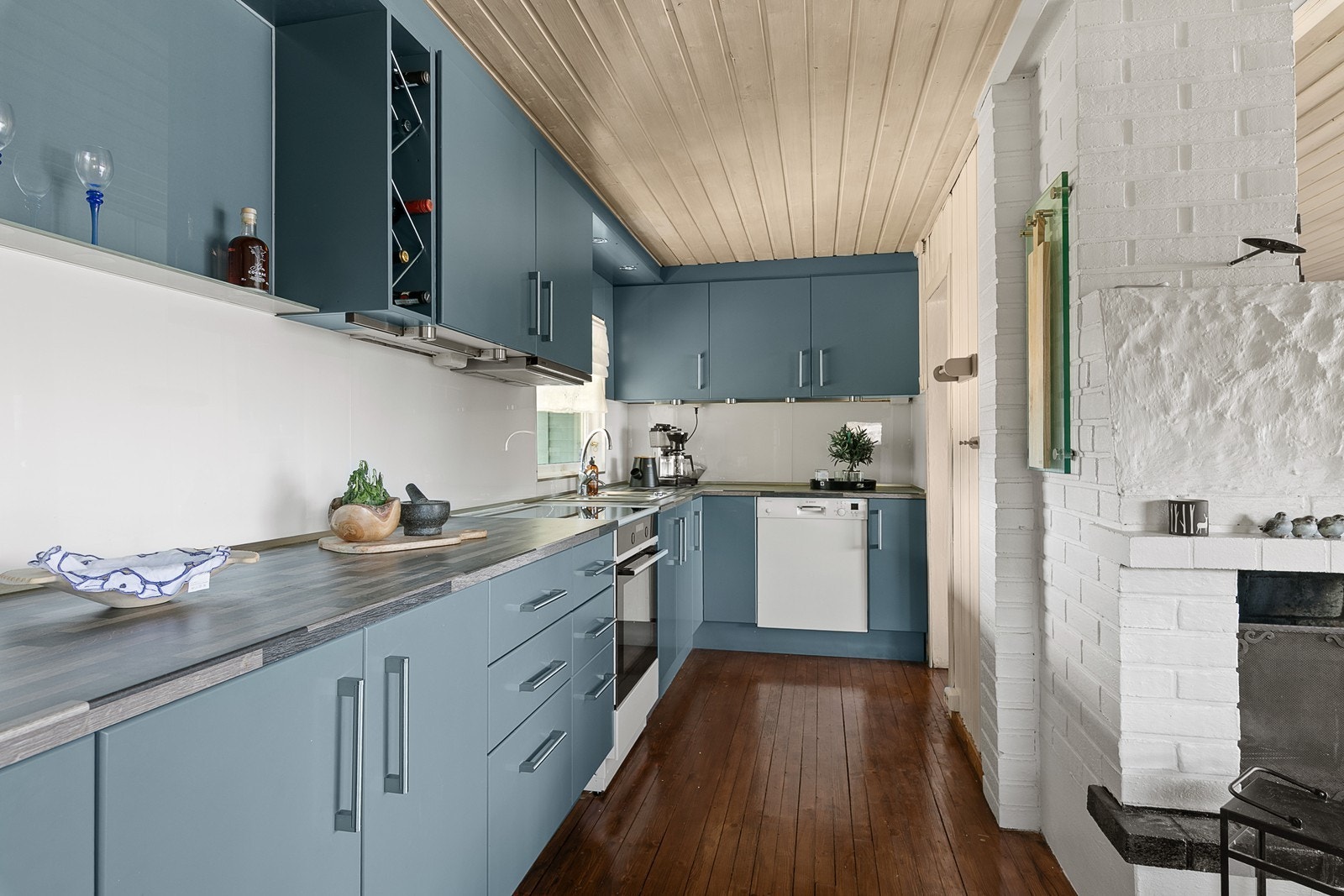 Kjøkkeninnredningen består av over og underskaper med slette fronter. Nisje for frittstående komfyr og integrert vaskemaskin. Galleribilde