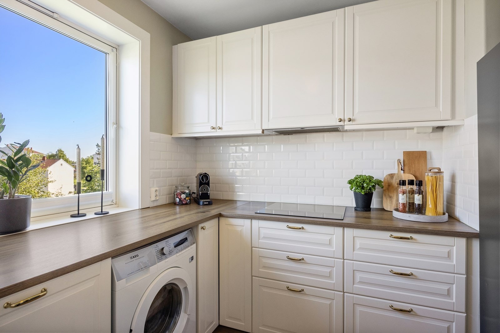 Kjøkkenet har profilerte, fabrikklakkerte fronter og laminatbenkeplate med nedfelt oppvaskkum, belyst av lysarmatur over vasken. Galleribilde