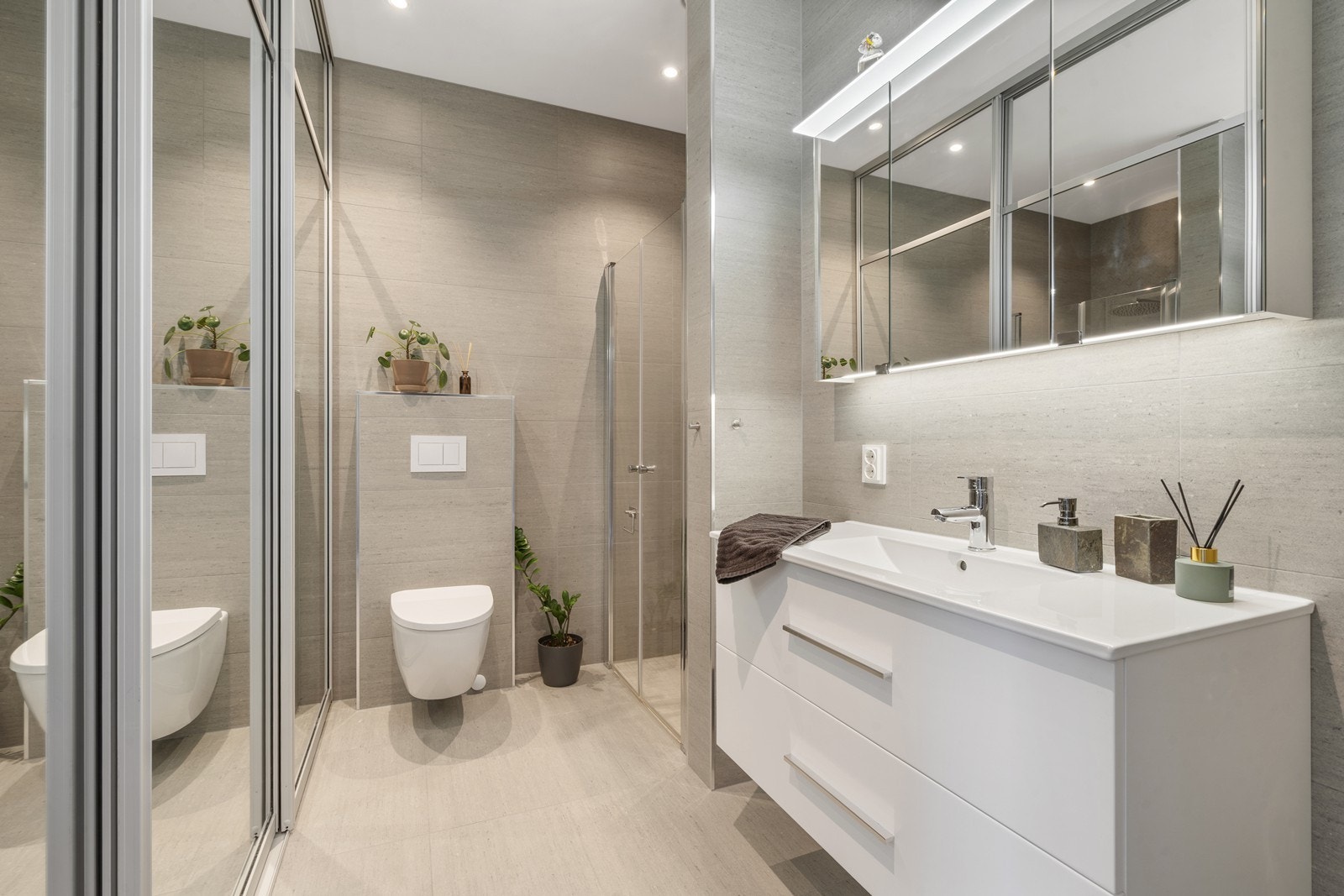 Bad/vaskerom underetasje: Lekkert og helsliset bad/vaskerom. Praktisk og flott skyvedrøsgarderobe med speil, opplegg for vaskemaskin og tørketrommel. Badet har dusjnisje, seksjon med heldekkende vask, vegghengt toalett Galleribilde