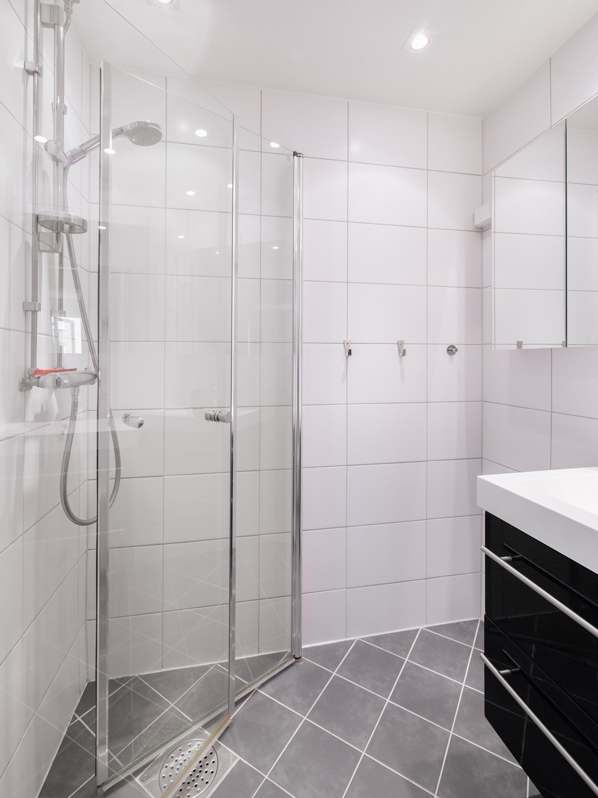 Badet er utstyrt med dusjhjørne med to svingbare glassdører, slett innredning med servant og etgreps blandebatteri, vegghengt toalett og opplegg for vaskemaskin. Galleribilde