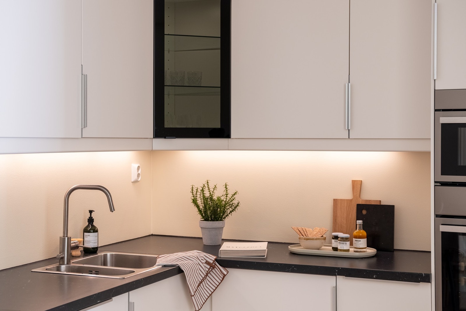 Ett overskap har innfelt glassfelt og belysning, i tillegg til at det er montert belysning og stikkontakter under skapene. Galleribilde