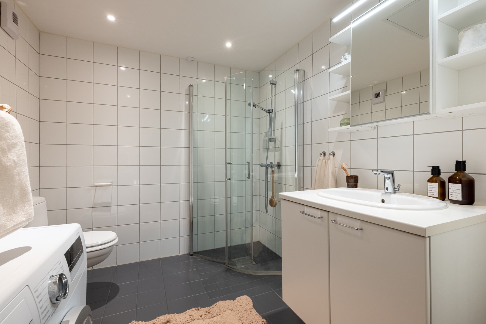 Fra gangen er det inngang til boligens baderom som er flislagt og pent, og med varme i gulv. Her er det opplegg for vaskemaskin. Galleribilde