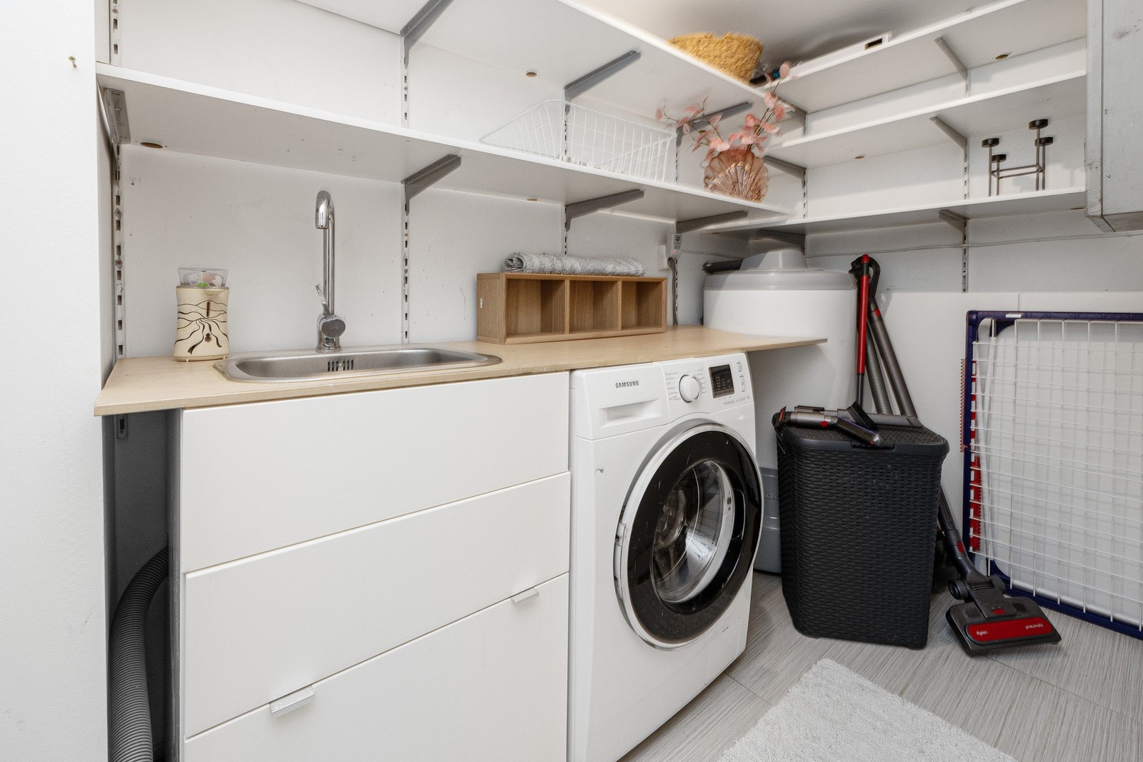 Vaskerommet har flislagt gulv, malte flater, servantinnredning med skuffer og opplegg for vaskemaskin. Galleribilde