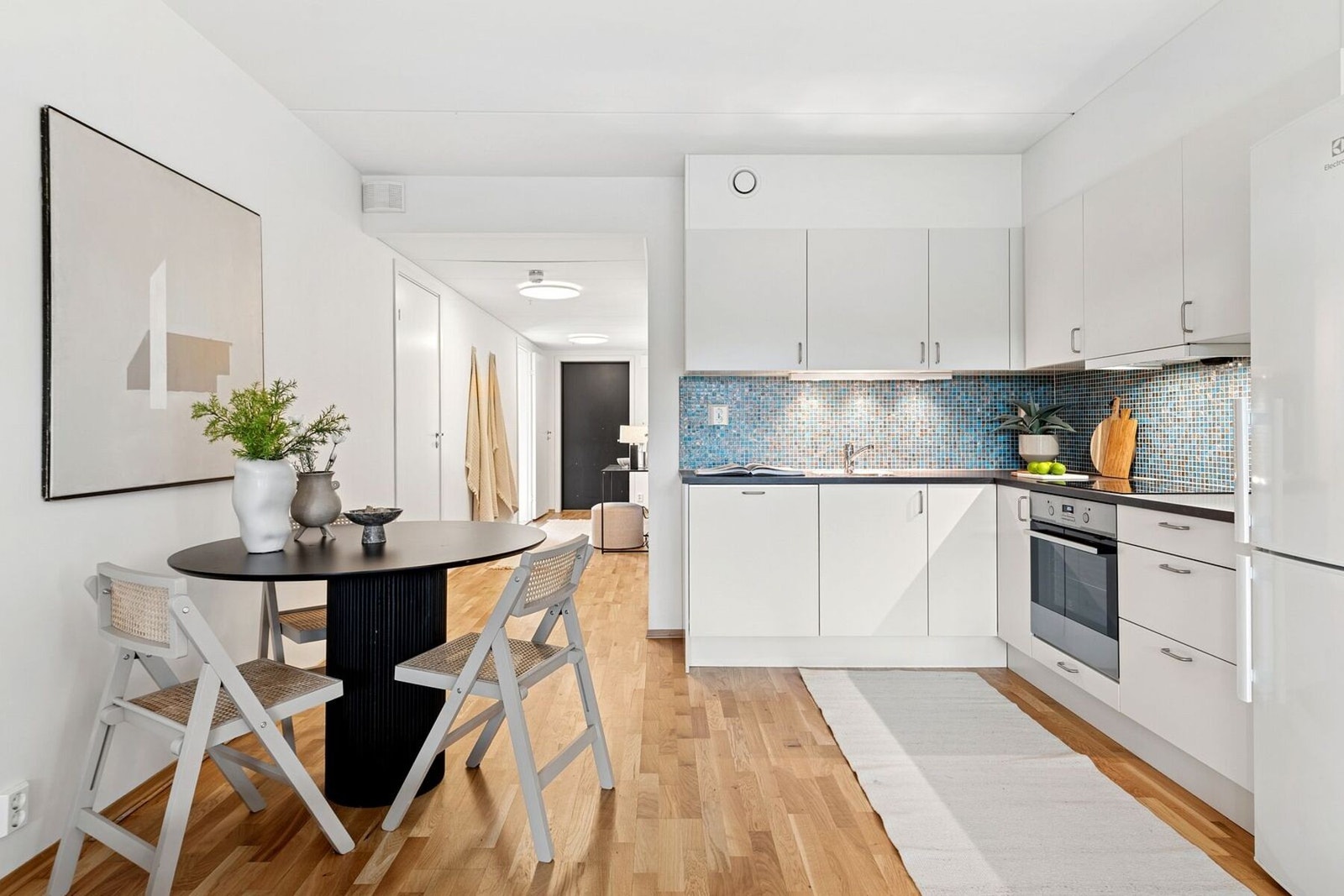 Kjøkkenet har innredning fra Norema og alle hvitevarer følger med. Innredningen har malte glatte fronter i hvit utførelse og laminat benkeplate. Galleribilde
