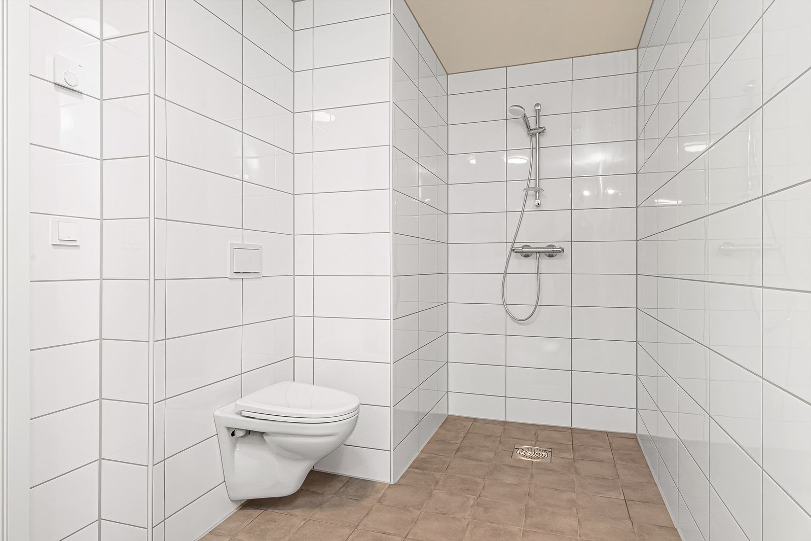 Badet er utstyrt med vegghengt toalett, dusj og servantmøbel Galleribilde