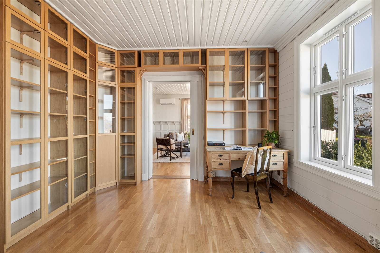 Både stuen og biblioteket har gyllent parkettgulv, og veggene og himlingen er hvitmalte. Det er downlights i biblioteket. Galleribilde