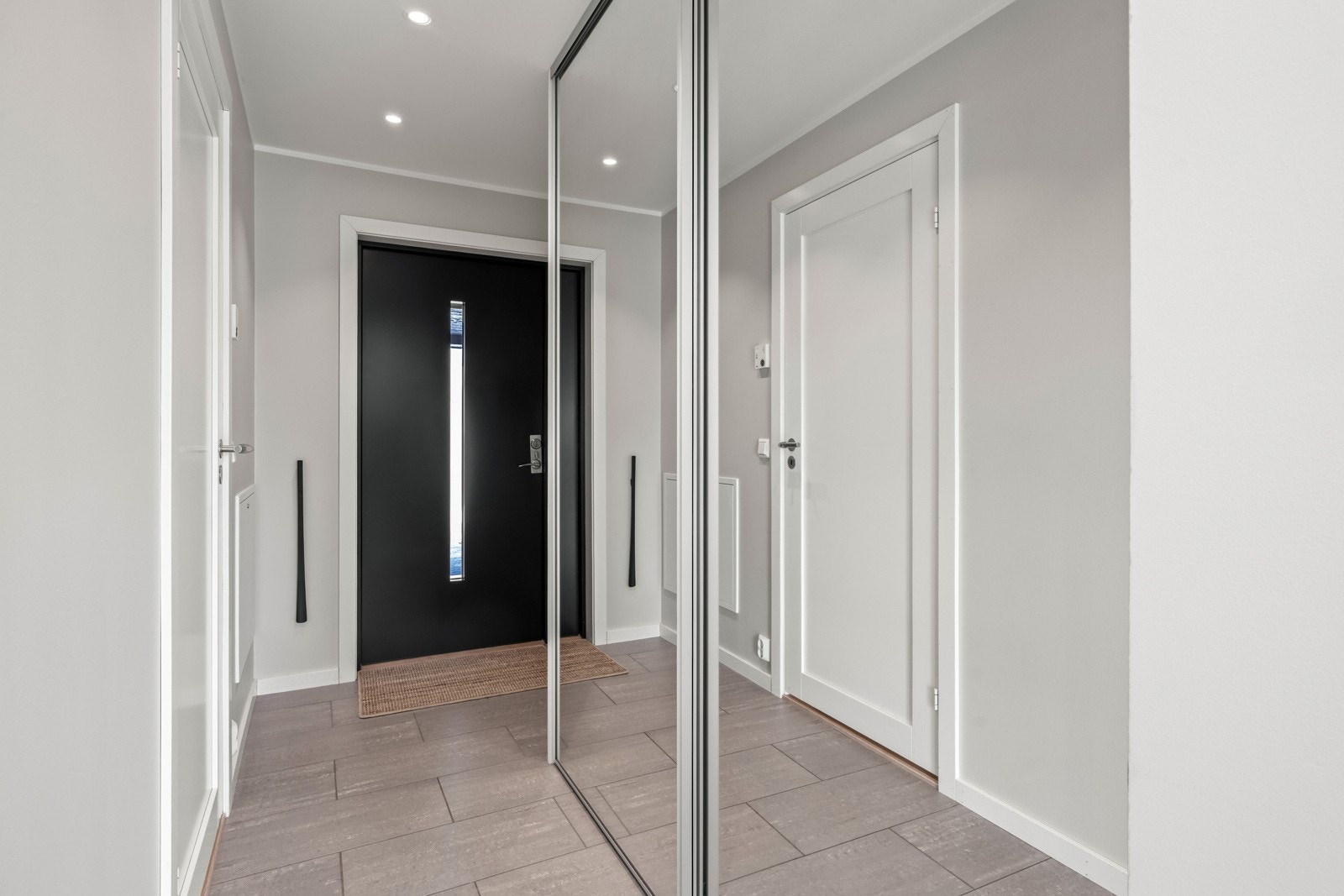 Flislagt inngangsparti med skyvedørsgarderobe. Galleribilde