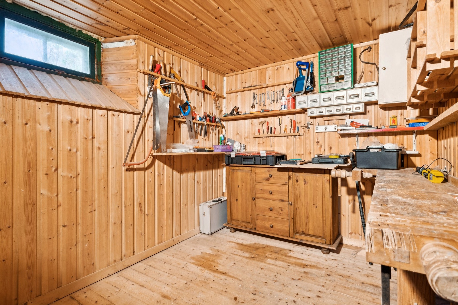 Innredet verksted med benk og hylleplass, perfekt for hobby eller verktøyoppbevaring. Galleribilde