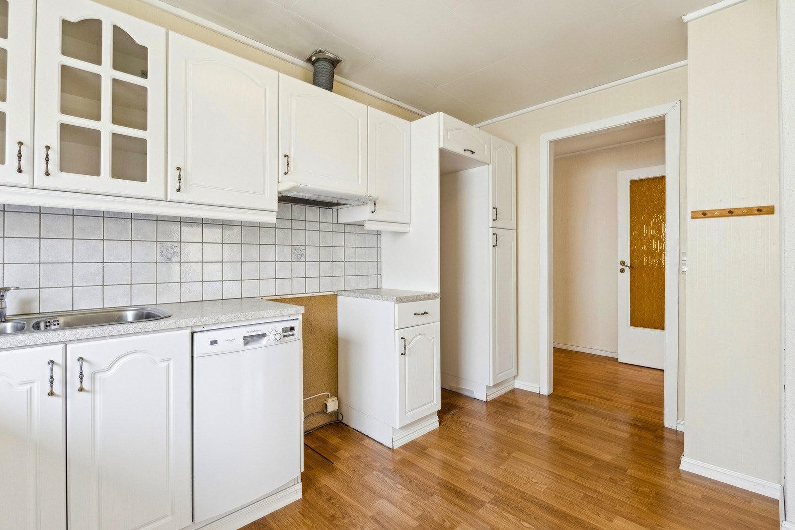 Hvit kjøkkeninnredning med godt med skapplass, plass til spisebord ved vinduet. Galleribilde