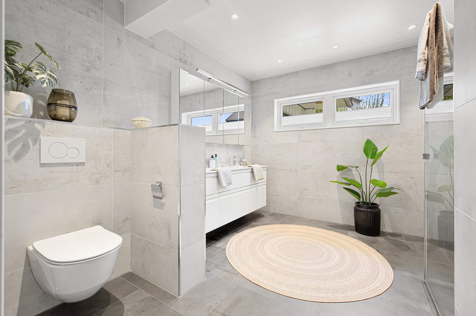 Delikat hovedbad med moderne flisvalg, vegghengt toalett og dobbelt servant. Galleribilde