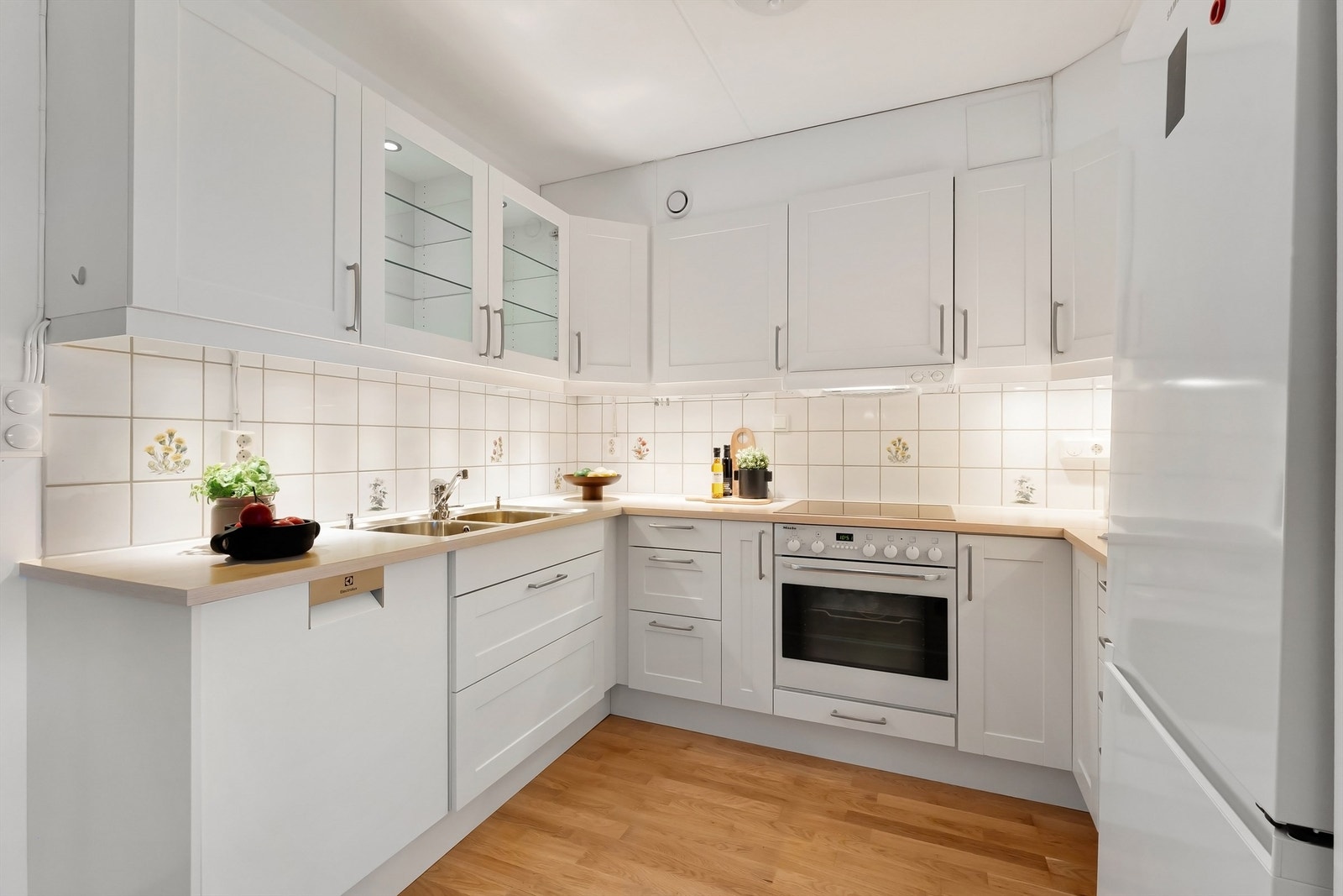 Kjøkkenet har profiterte fronter på skap og skuffer, benkeplate av laminat med planlimt oppvaskkum og veggfliser over kjøkkenbenken Galleribilde