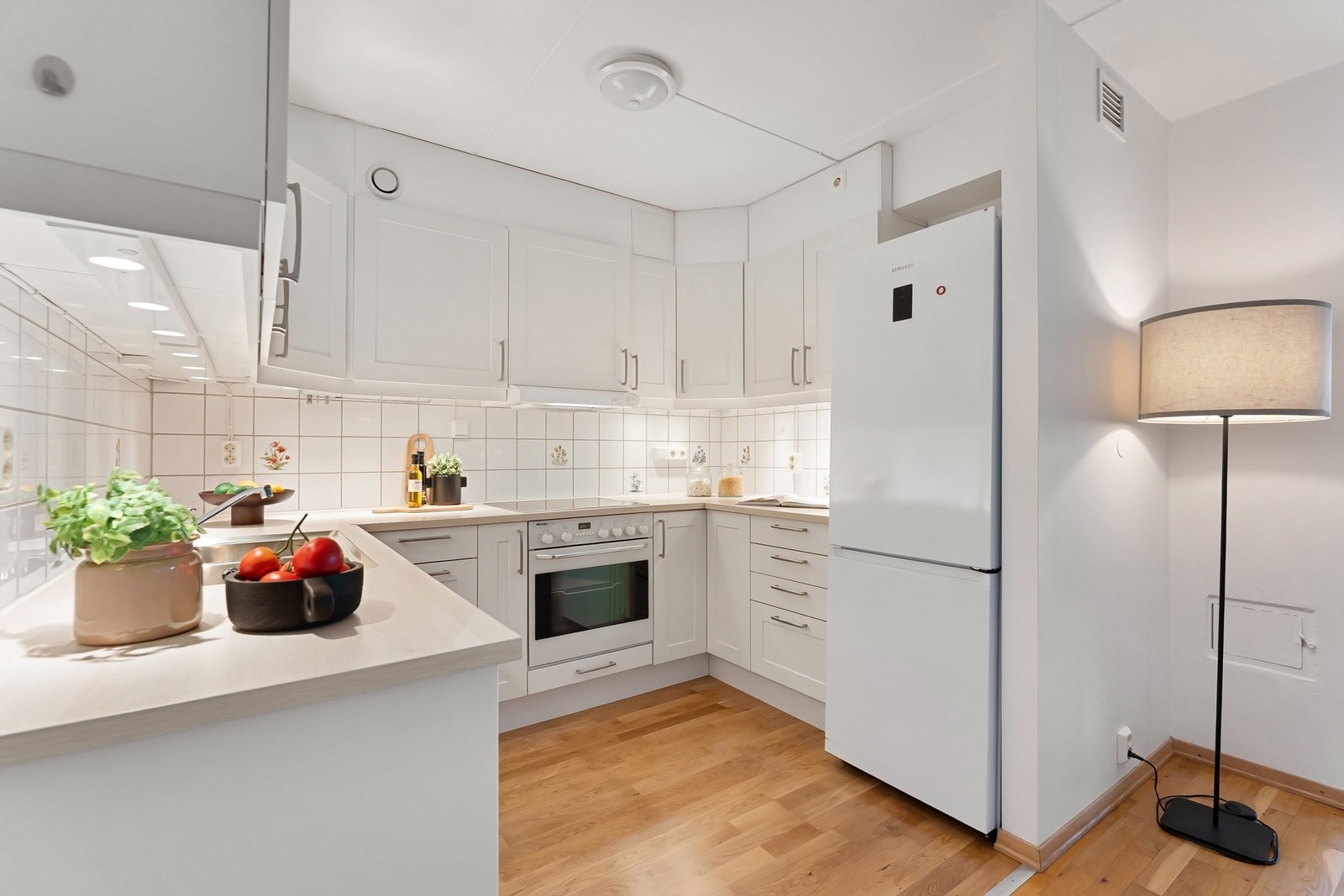 Kjøkkenet har integrert induksjonsplatetopp, stekeovn, oppvaskmaskin og plass for frittstående kjøleskap Galleribilde