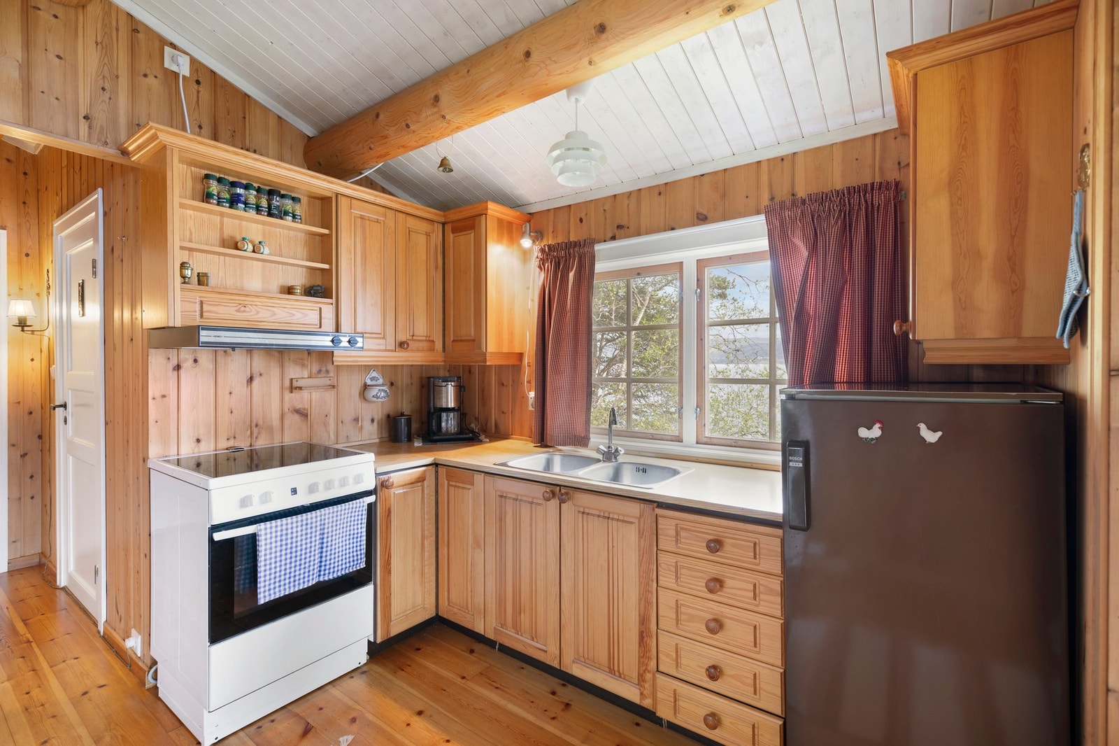 Kjøkken med L-formet innredning med heltrefronter, samt opplegg for frittstående hvitevarer Galleribilde