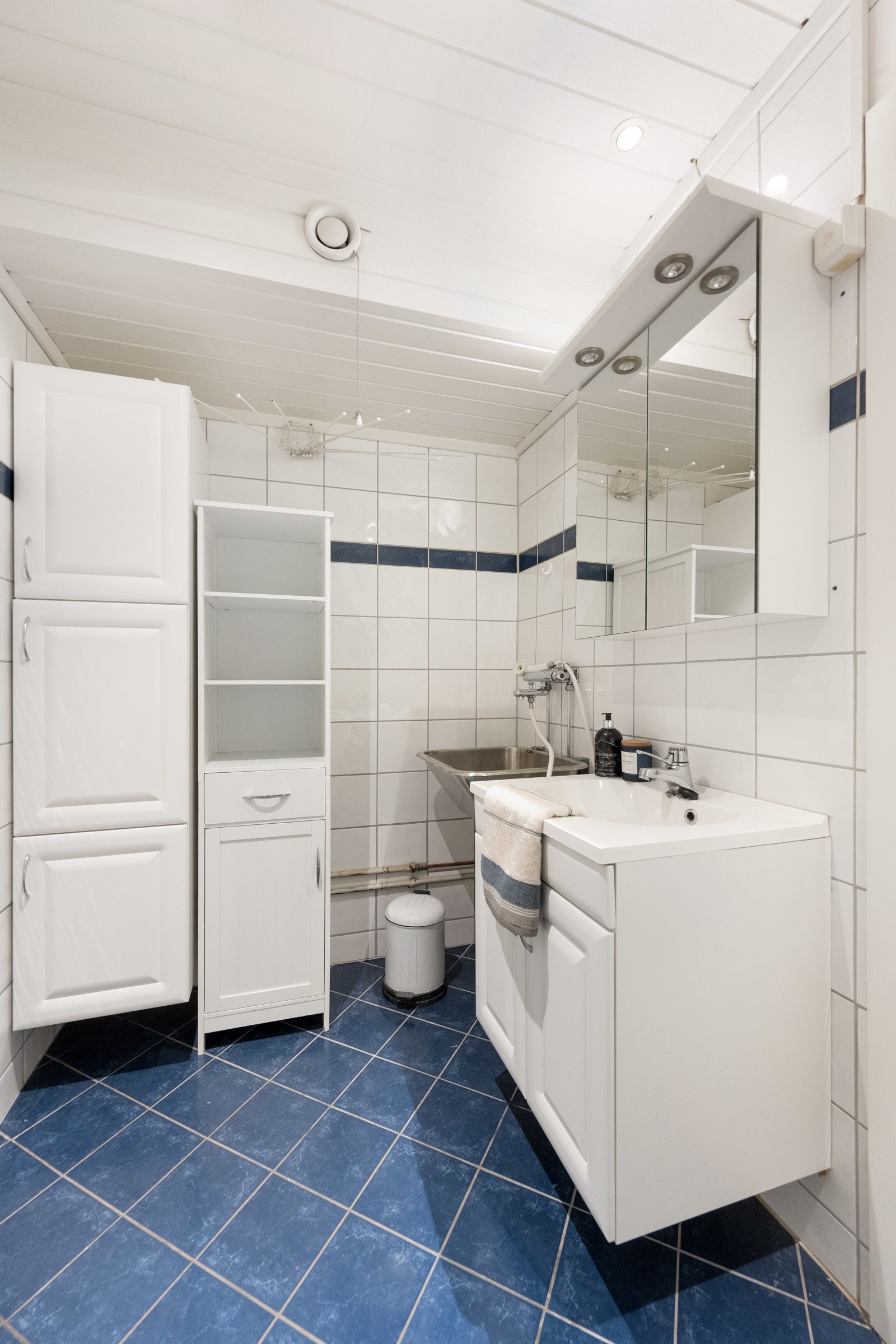 Flislagt bad med hvit innredning og skyllekum. Galleribilde