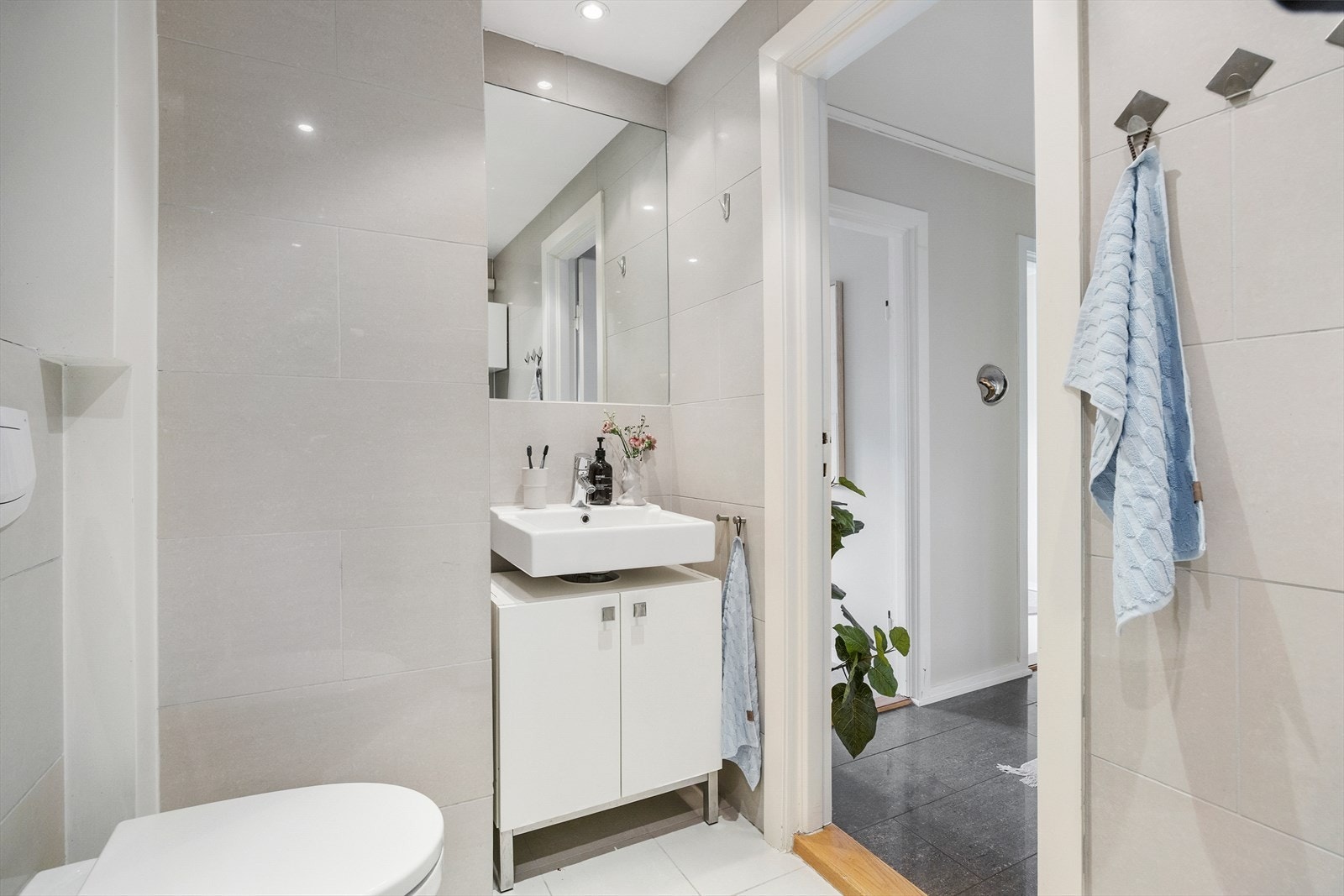 Badet inneholder vegghengt toalett, dusjnisje med glassdører, servant med skap under, veggmontert speil og downlights i himling. Mekanisk avtrekksvifte. Galleribilde