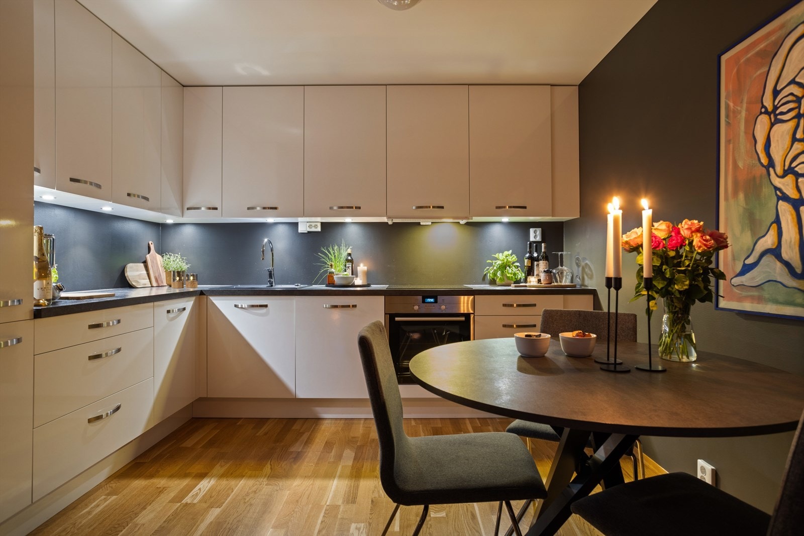 Kjøkkeninnredningen har hvite glatte fronter og en mørk benkeplate av laminat, med integrerte hvitevarer av kjøl/fryseskap, oppvaskmaskin, platetopp, stekeovn og komfyrvakt. Galleribilde