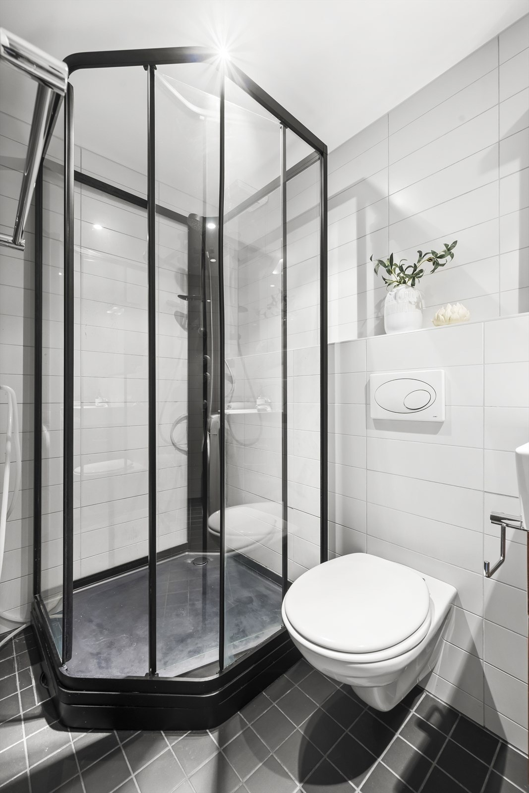 Badet er innredet med vegghengt toalett, servant nedfelt i innredning og dusjkabinett. Galleribilde