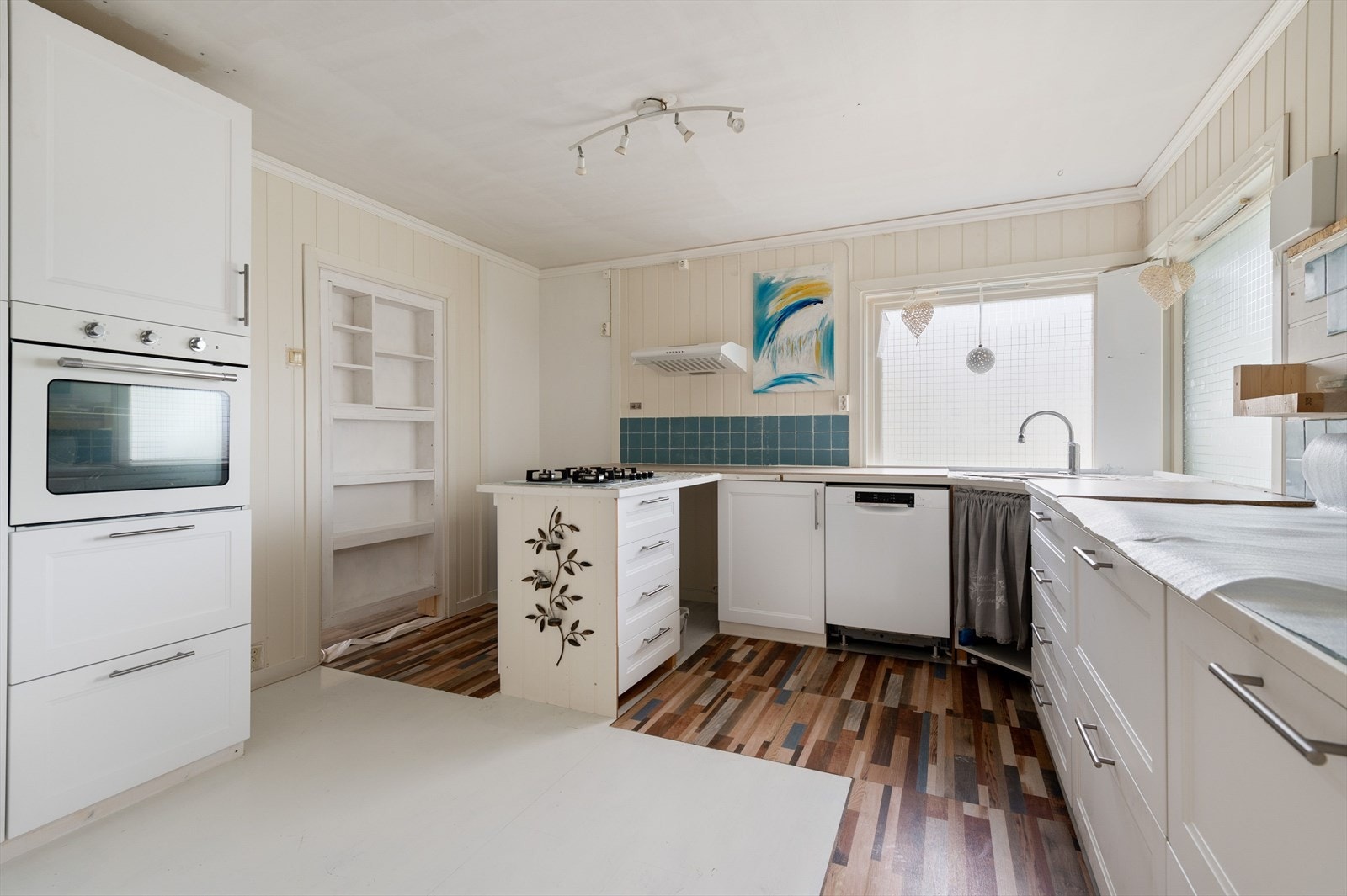 Kjøkken med lys kjøkkeninnredning, integrert stekeovn og koketopp på gass. Galleribilde