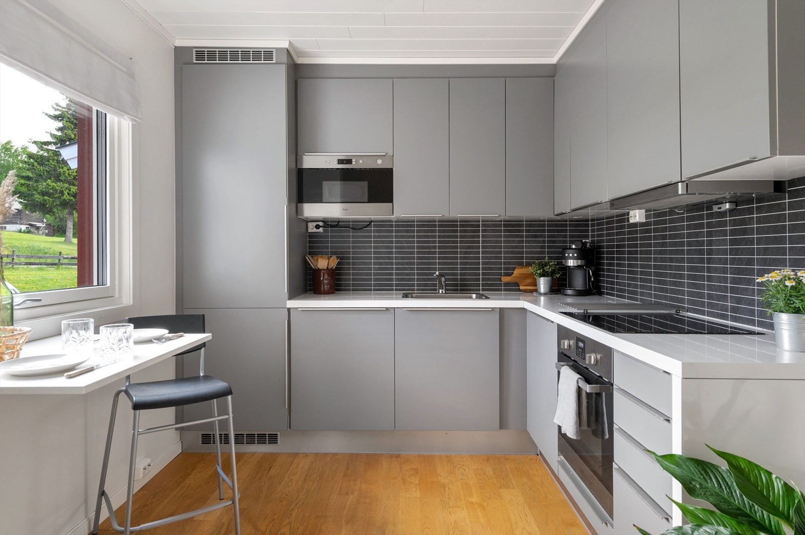 Pent kjøkken med grå, glatte fronter. Integrerte hvitevarer. Galleribilde