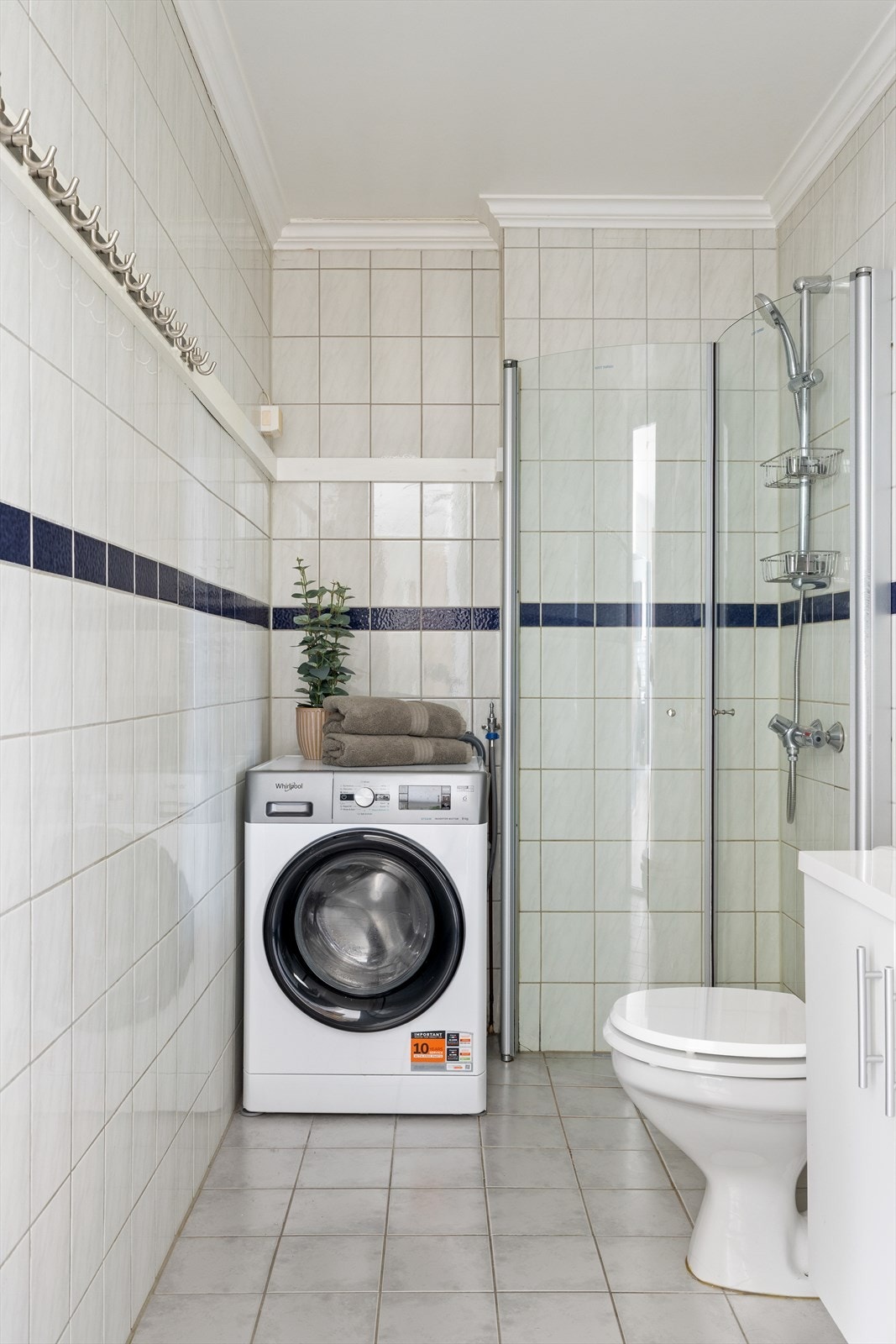 Flislagt baderom med gulvmontert toalett, innredning med servant og dusj/vegger. Ventilering via avtrekksventil i tak og luftespalte i dør. Galleribilde