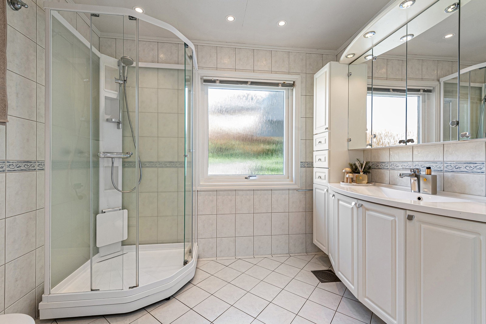 Badet i hovedetasjen ble oppgradert ca. 2003 iflg eier og har flislagt gulv med gulvvarme, flislagte vegger og takplater i tak med innfelte spotter. Dusjakabinett med dusjarmatur. Gulvstående toalett. Galleribilde