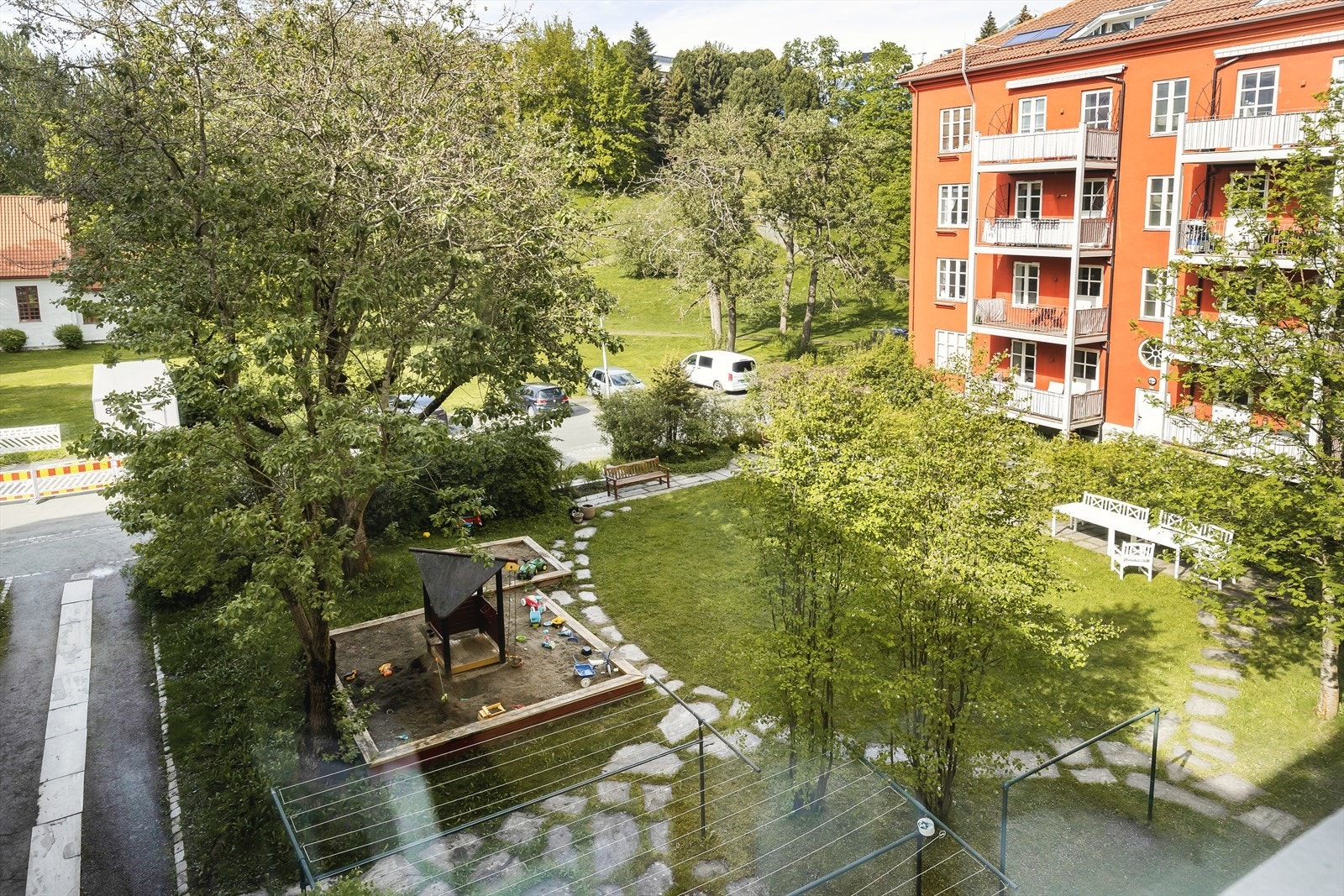 Frodig bakgård med grøntareal, lekeplass, sittegrupper og bålplass. Galleribilde