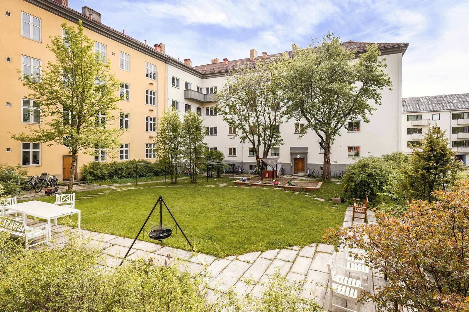 Frodig bakgård med grøntareal, lekeplass, sittegrupper og bålplass. Galleribilde