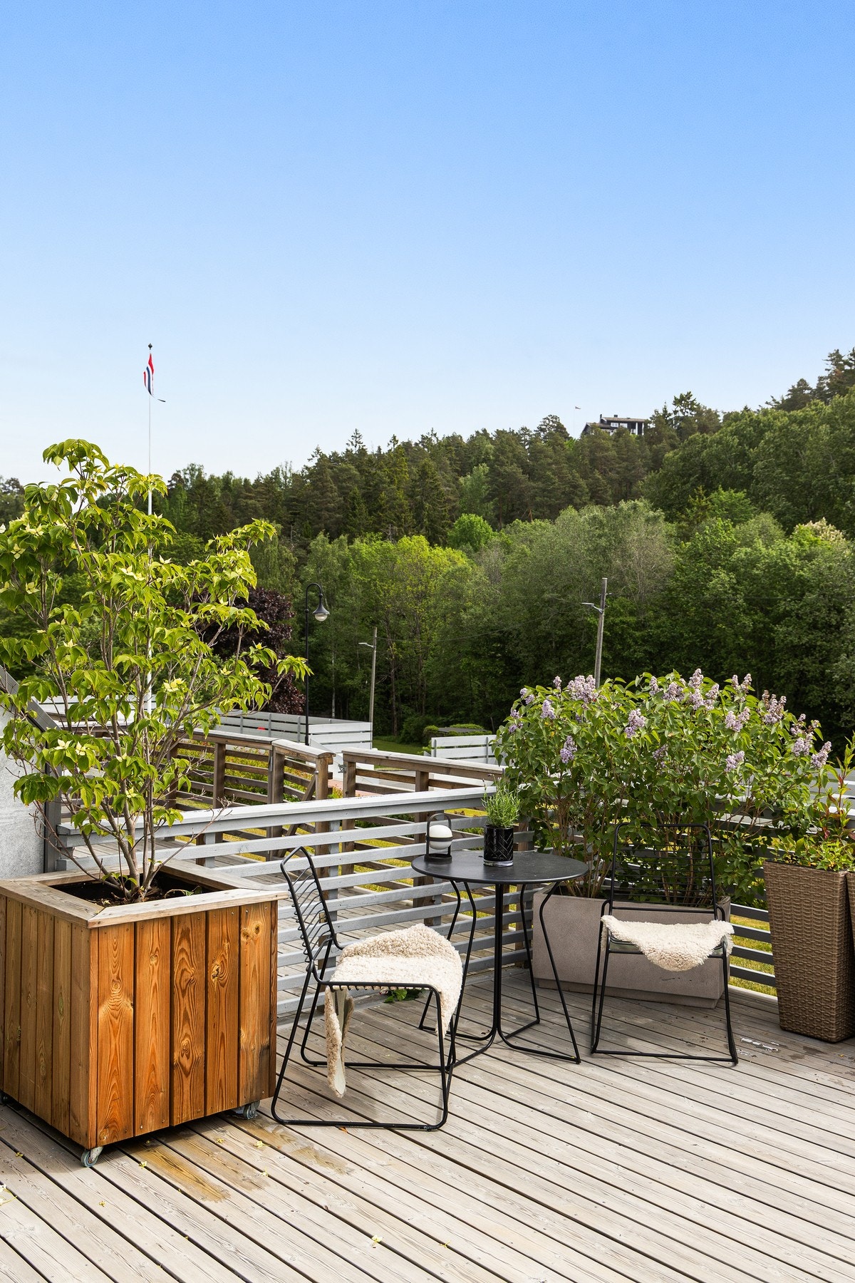 Terrassen vender ut mot et frodig og grønt fellesareal med store plener og skog - en idyllisk ramme rundt en svært attraktiv uteplass. Galleribilde