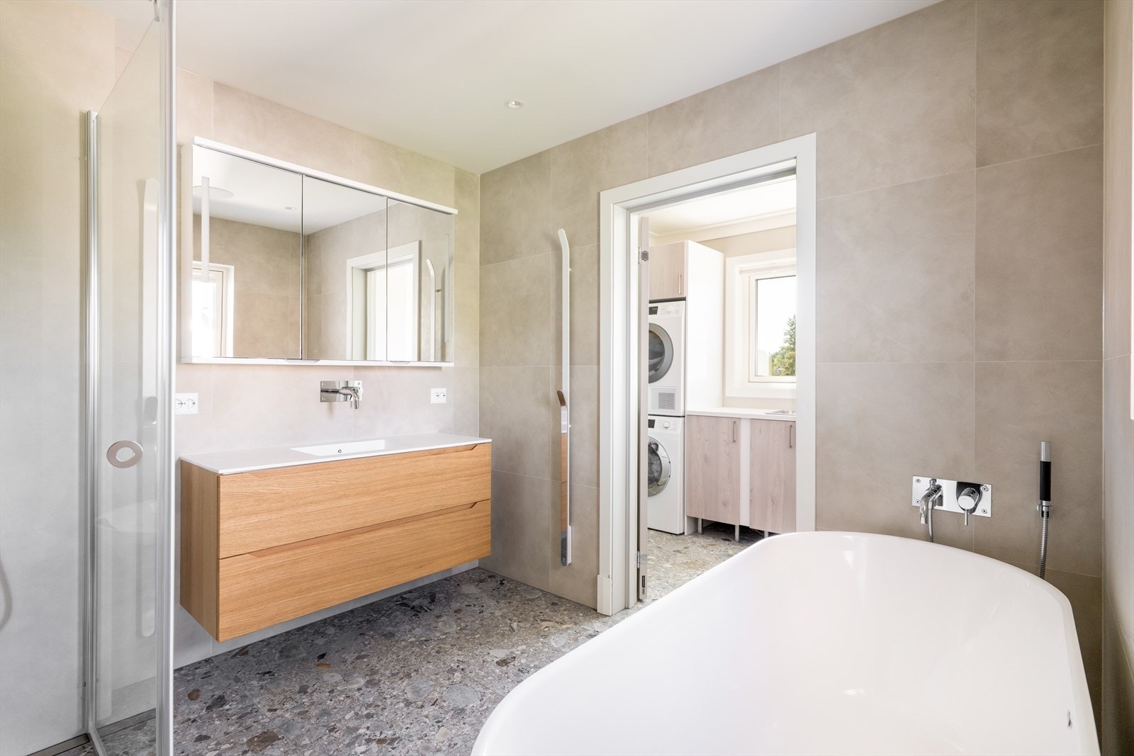 Her er det en pen innredning fra Linn Bad med heldekkende hvit vask, underskuffer med slette fronter og overskap med speildører. Det er dusjhjørne med glassdører, vegghengt toalett og badekar. Rommet er mekanisk ventilert. Galleribilde