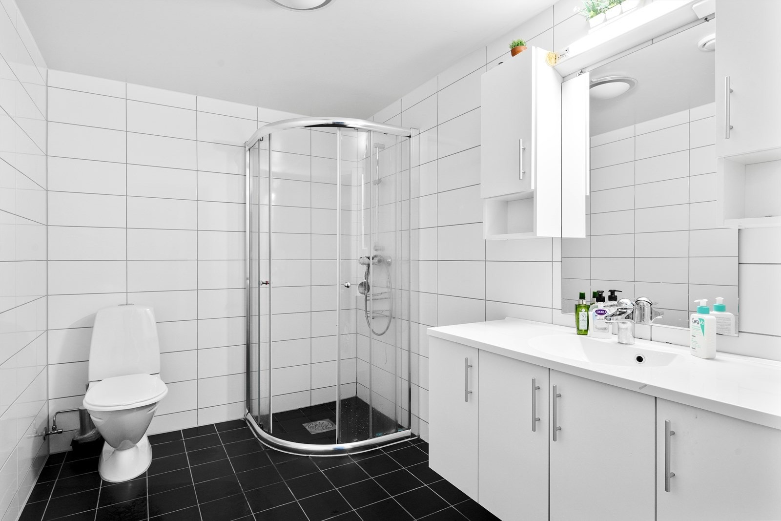 Helfliset bad med varmekabler i gulv. Badet er innredet med servant i baderomsinnredning, toalett og dusjhjørne. Galleribilde