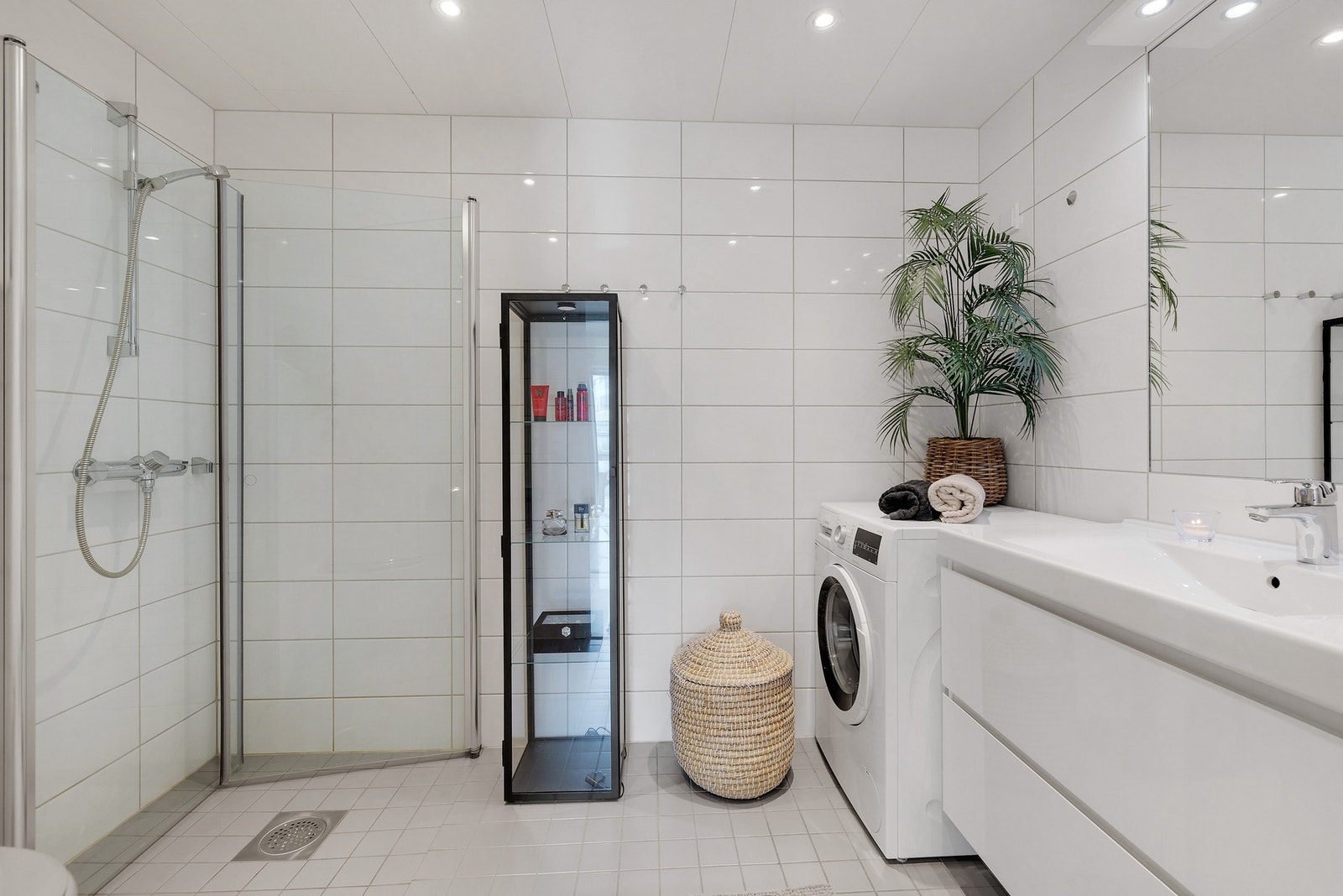 Flott baderom med dusj, servantinnredning og opplegg for vaskemaskin. Galleribilde