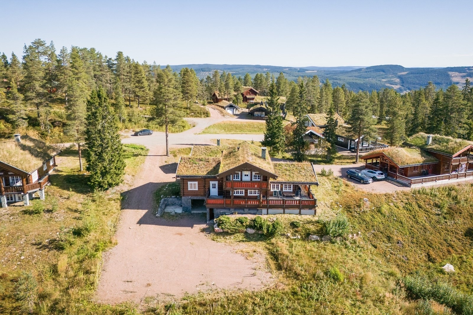 Hytten ligger åpent og fritt på romslig tomt med garasje i underetasje med direkte adkomst til hytten og stor gruset gårdsplass med plass til mange biler. Galleribilde