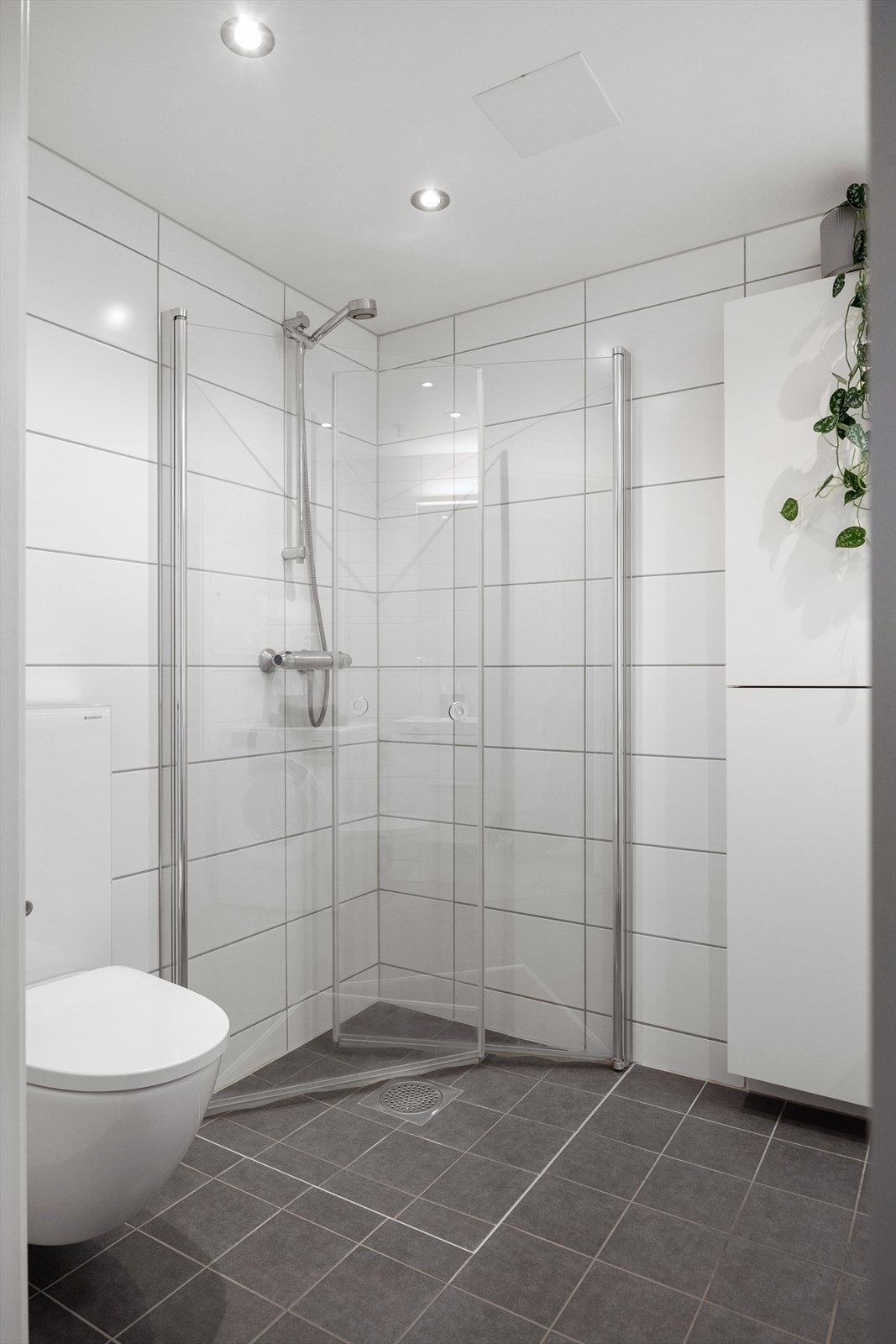 Rommet er praktisk innredet med vegghengt toalett, servant integrert i møbel, dusjhjørne med svingbare glassdører og opplegg for vaskemaskin. Galleribilde